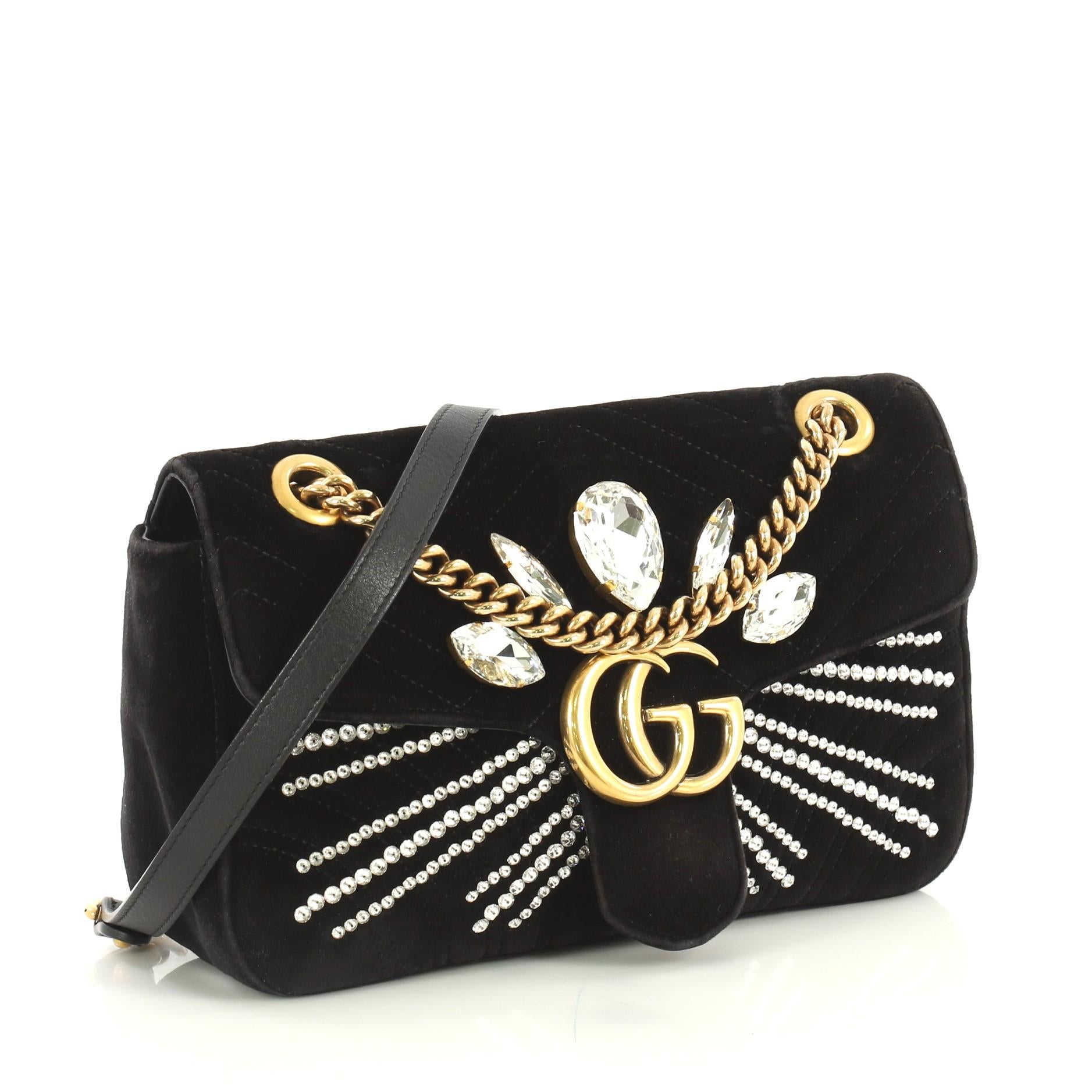 This Gucci GG Marmont Shoulder Bag Crystal Embellished Matelasse Velvet Small, crafted from black matelasse velvet, features chain link strap with leather pad, GG logo and crystal embellishments, and aged gold-tone hardware. Its push-lock closure