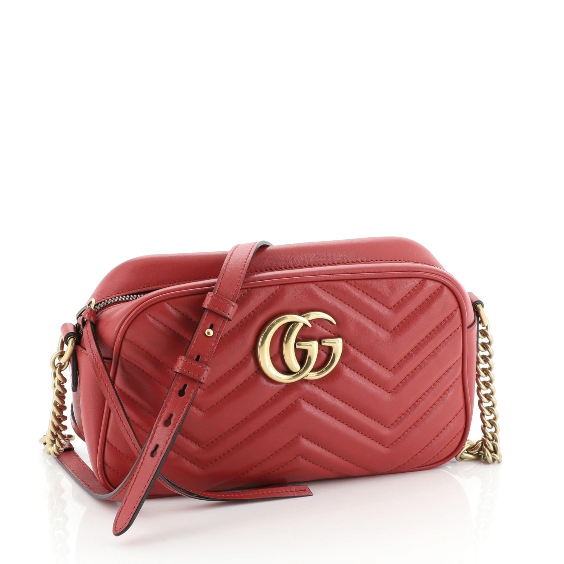 This Gucci GG Marmont Shoulder Bag Matelasse Leather Small, crafted from red matelasse leather, features a leather strap with chain links, GG logo at the front, and aged gold-tone hardware. Its zip closure opens to a neutral microfiber interior with