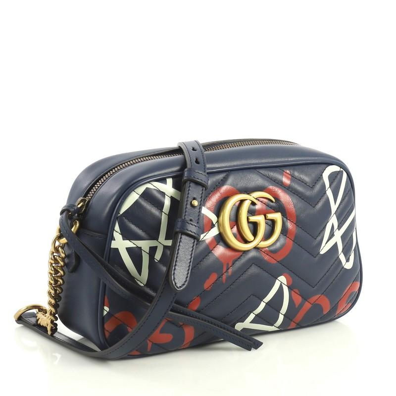 This Gucci GG Marmont Shoulder Bag GucciGhost Matelasse Leather Small, crafted in blue matelasse leather, features adjustable leather strap with chain links, interlocking GG logo, and aged gold-tone hardware. Its zip closure opens to a neutral