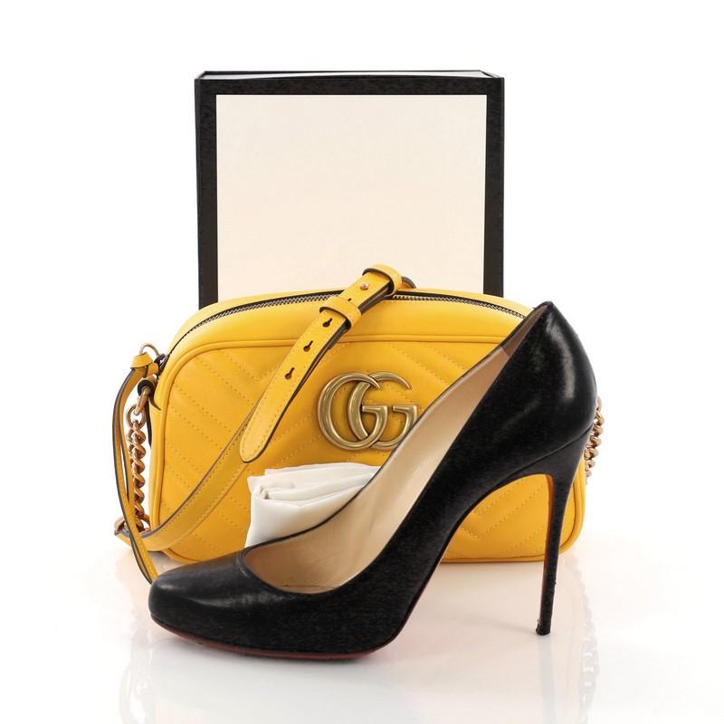 This Gucci GG Marmont Shoulder Bag Matelasse Leather Small, crafted from yellow matelasse leather, features a leather strap with chain links, GG logo at the front, and aged gold-tone hardware. Its zip closure opens to a light pink microfiber