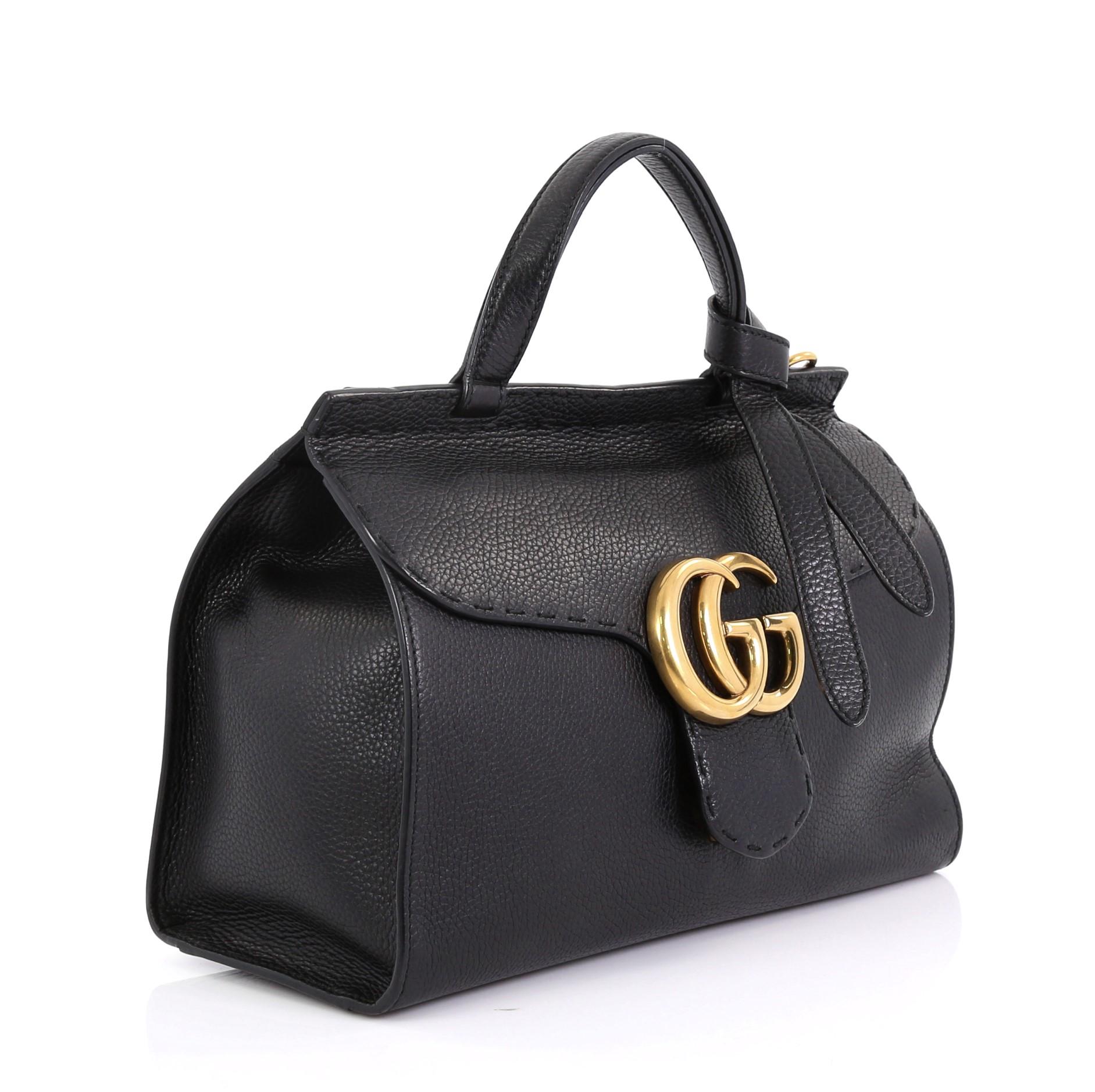 This Gucci GG Marmont Top Handle Bag Leather Small, crafted from black leather, features a flat leather handle, flap top with GG logo, and aged gold-tone hardware. Its push-lock closure opens to a beige fabric interior with zip pocket. 

Estimated