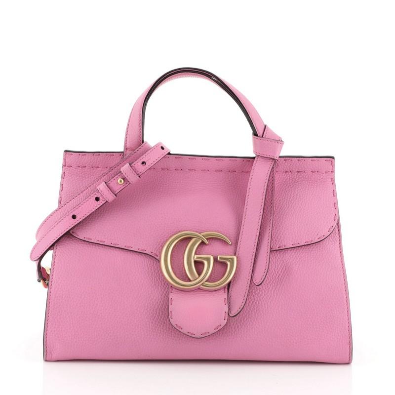 This Gucci GG Marmont Top Handle Bag Leather Small, crafted from pink leather, features a flat leather handle, flap top with GG logo, and gold-tone hardware. Its push-lock closure opens to a neutral fabric interior with zip and slip pockets.