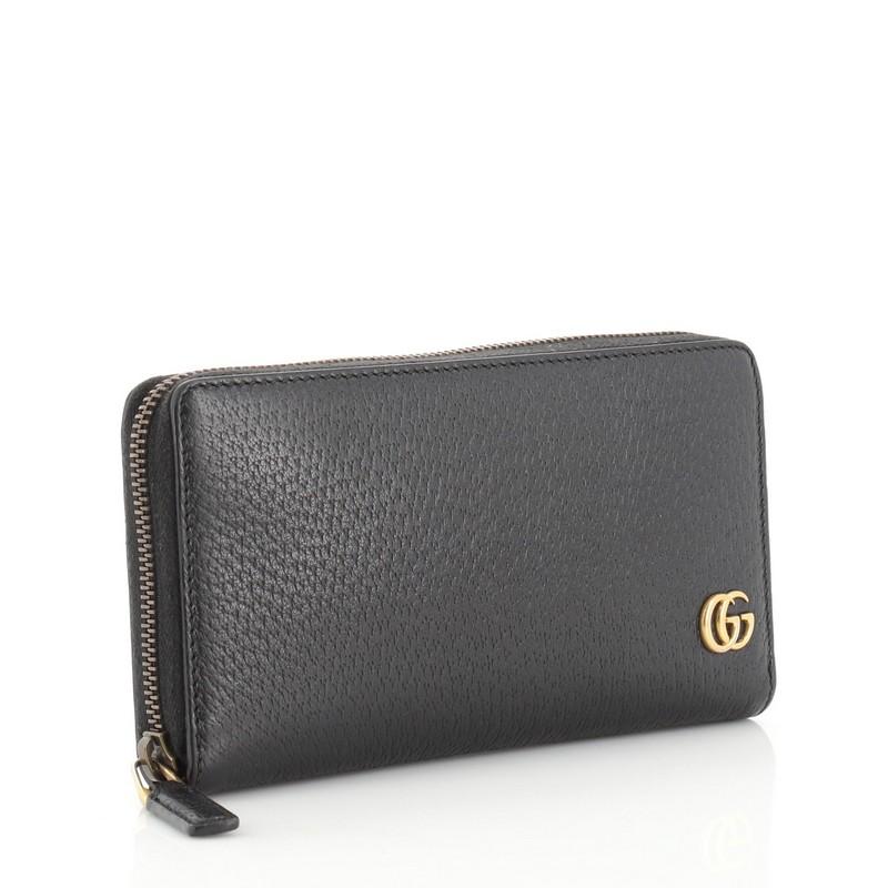 This Gucci GG Marmont Zip Around Wallet Leather, crafted in black leather, features double G logo at front and aged gold-tone hardware. Its zip-around closure opens to a black leather interior with multiple card slots, center zip pocket and slip