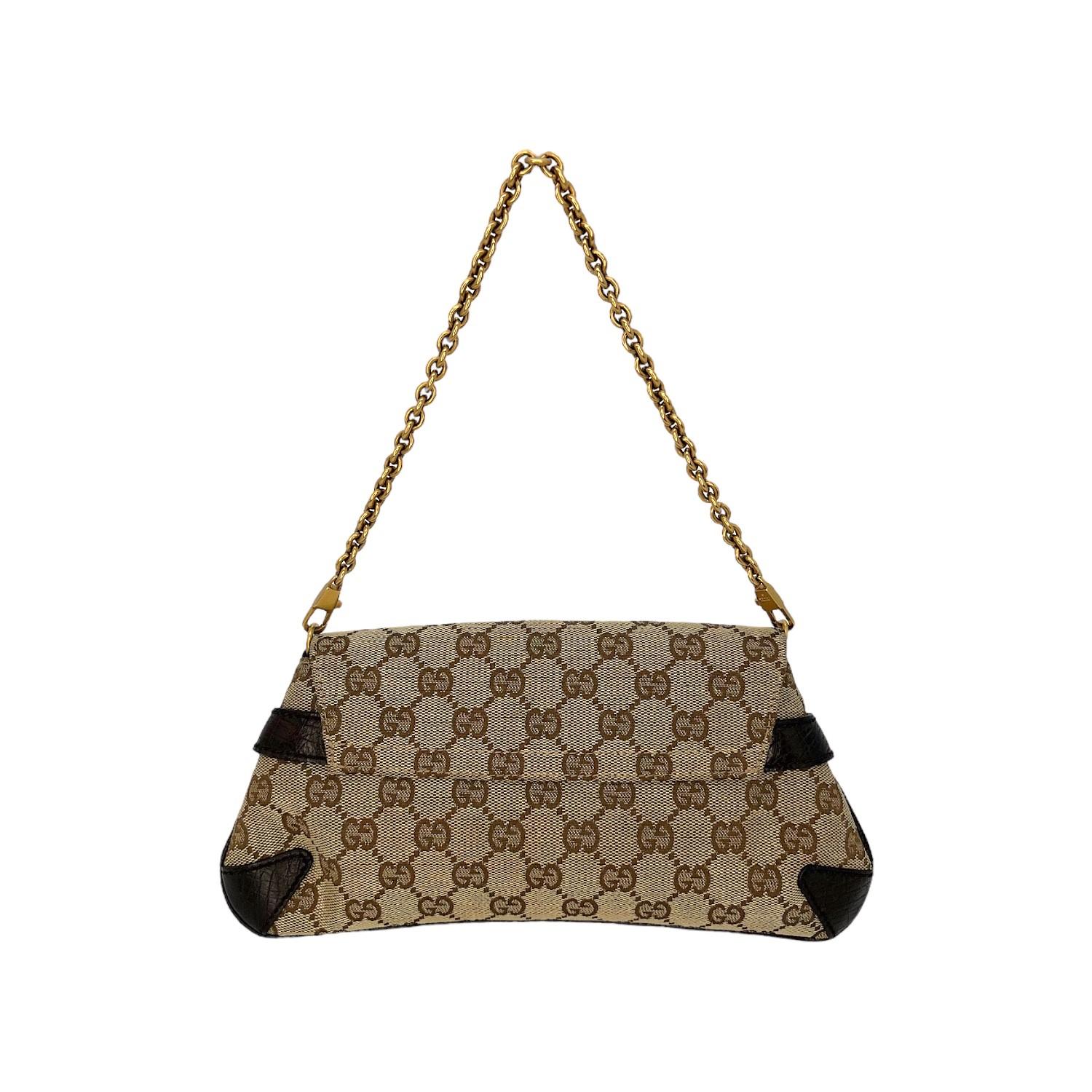 This Gucci Horsebit Clutch was made in Italy and it is finely crafted of the classic Gucci GG Monogram coated canvas with leather trimming and gold-tone hardware features. It has a removeable chain-link handle. It has a fold over closure that opens
