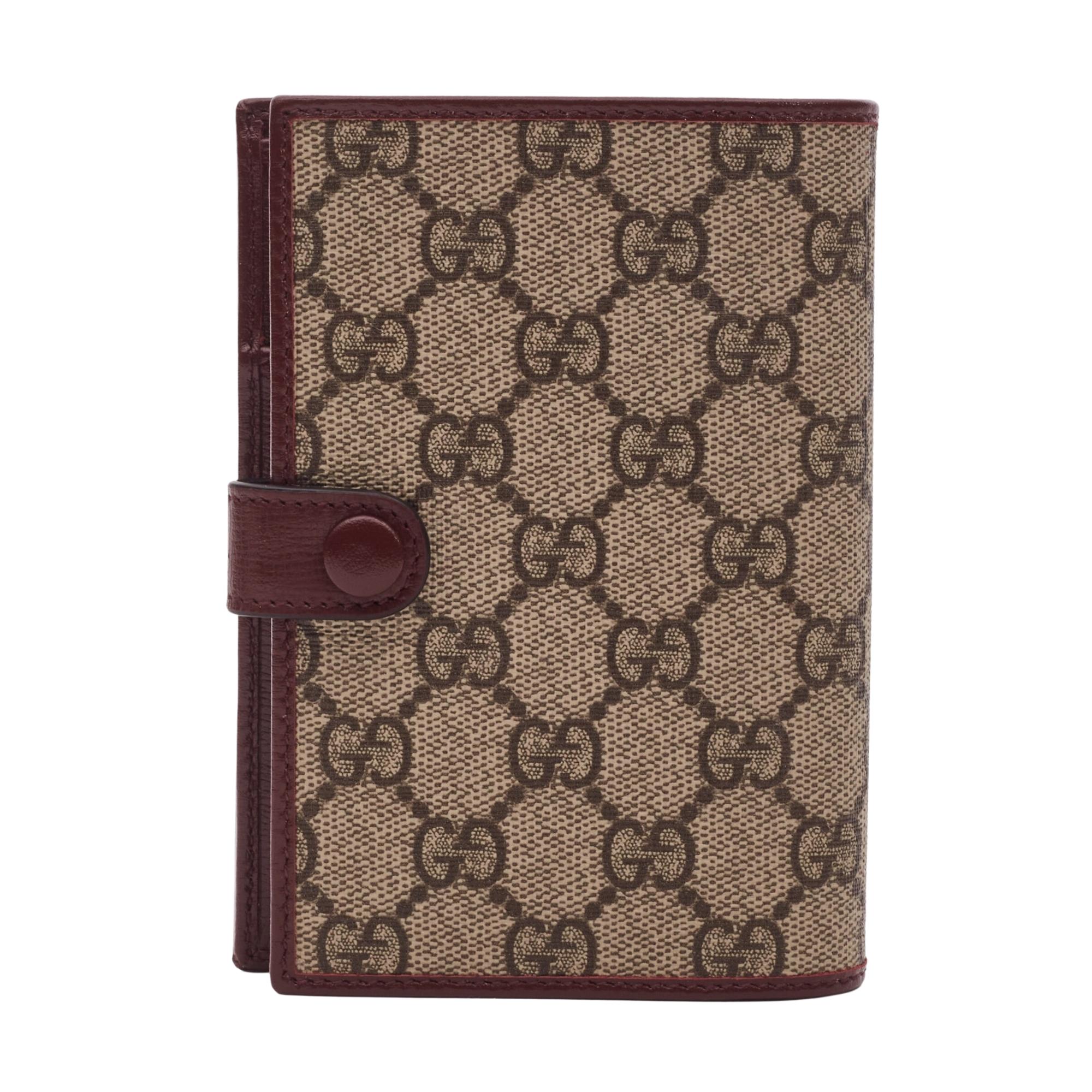 This classic looking Gucci passport case is made of signature beige and ebony GG Supreme canvas with leather detailing. The case features brown leather trim, snap-button closure, and an interior with a passport pocket, 3 open pockets, and 3 card