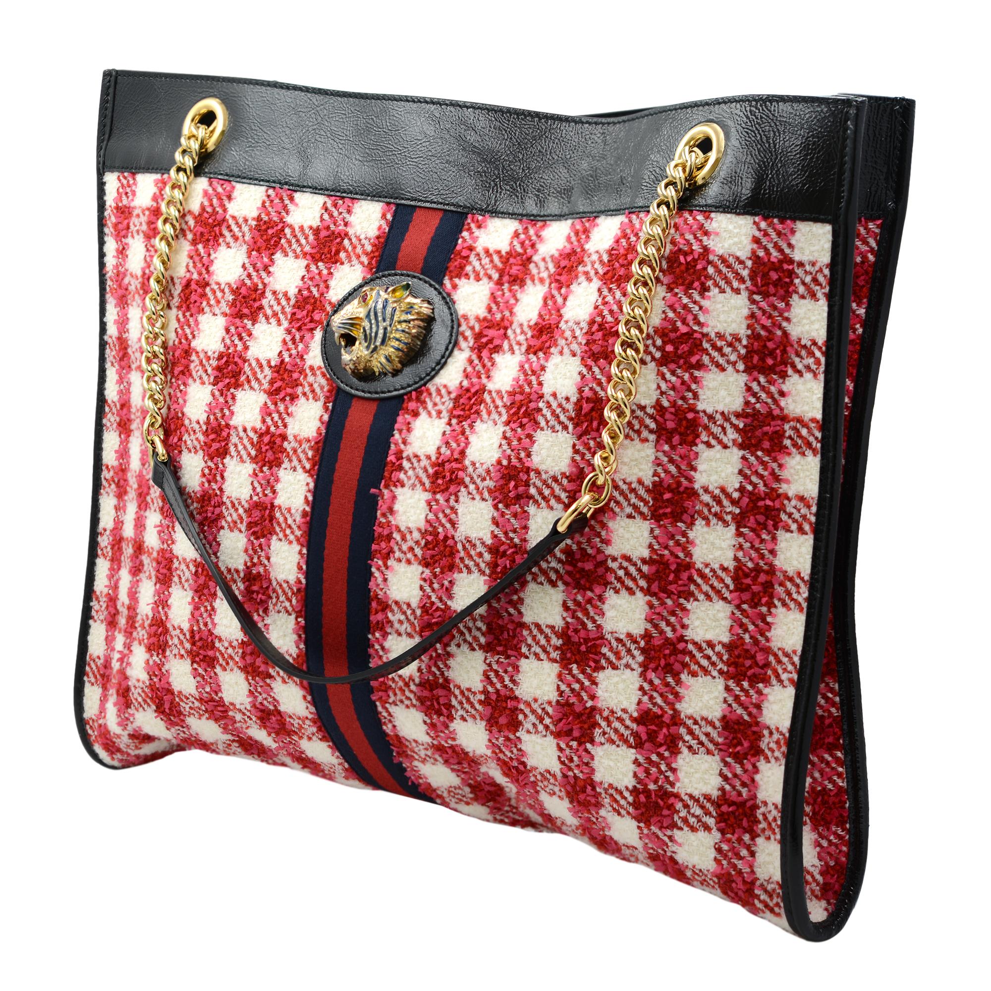 This stylish Gucci Rajah shoulder bag is finely crafted of woven red and white printed tweed with black leather trim. The bag features a prominent crystal-encrusted tiger head medallion on the front, red and blue web striping, and gold chain-link