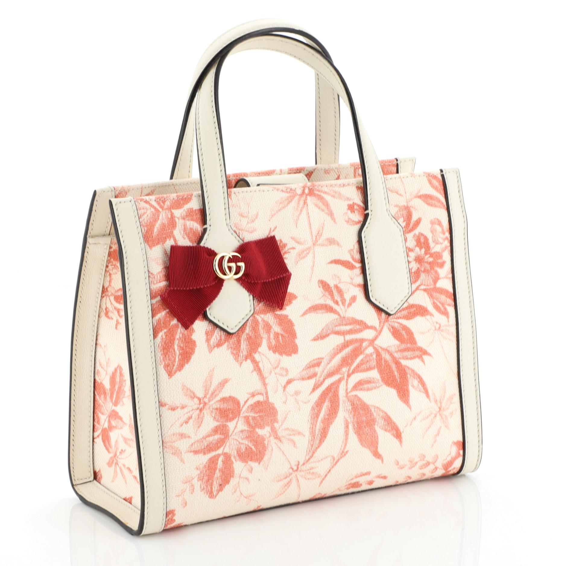 This Gucci GG Ribbon Tote Printed Linen Small, crafted from printed fabric, features dual flat leather handles, GG emblem and bow, and gold-tone hardware. Its magnetic closure opens to a white canvas interior with slip pockets. 

Estimated Retail