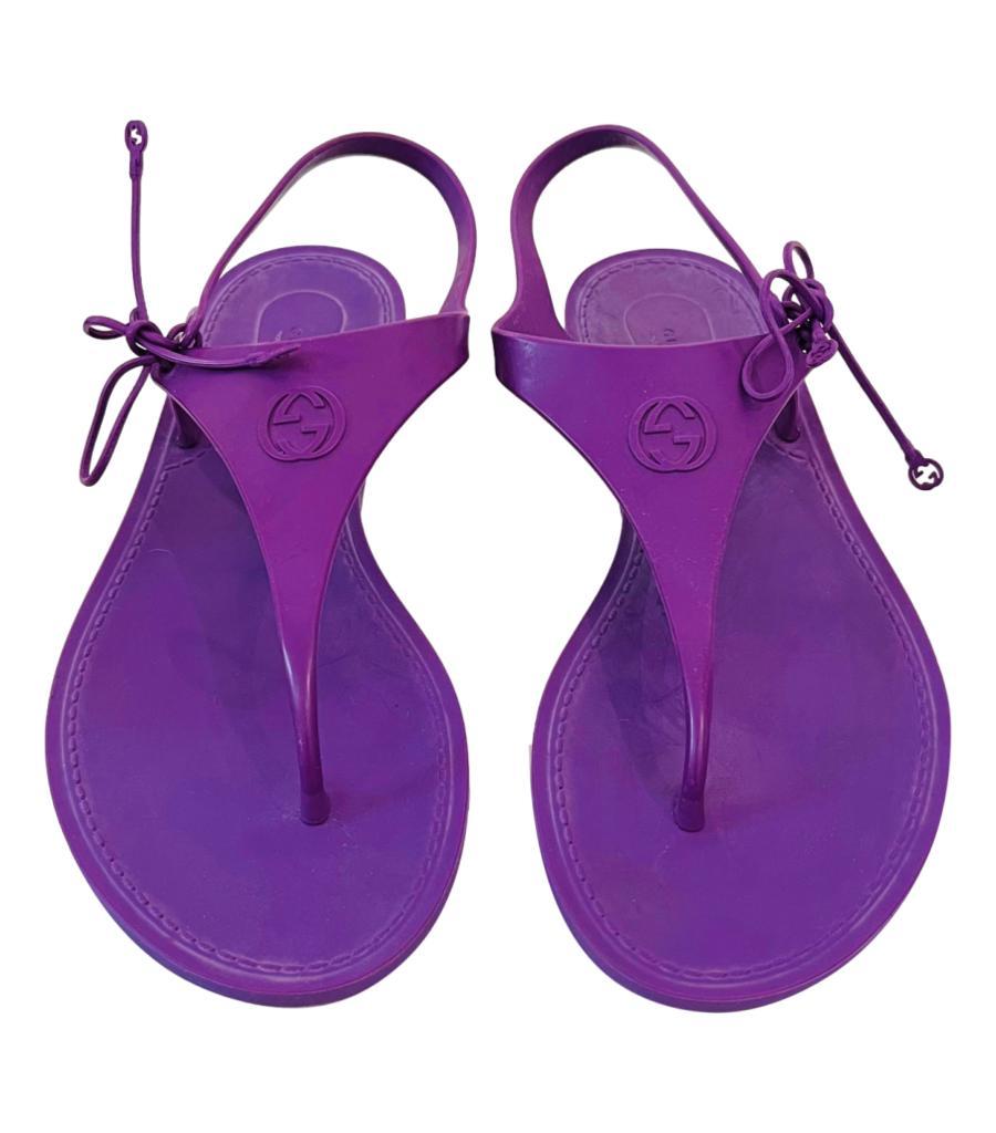 Gucci 'GG' Rubber Flip-Flop Sandals

Purple T-Strap sandals with Interlocking 'G' logo to the centre.

Featuring tie-up fastening to the side detailed with two Gucci logos.

Size – 24cm (Size missing)

Condition – Good (General signs of