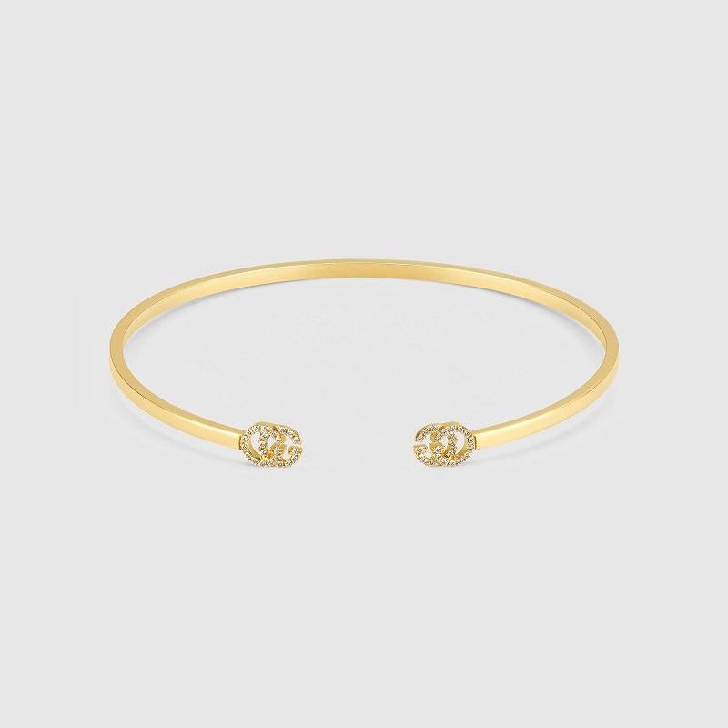 The Double G, inspired by an archival design from the '70s-a hallmark era of the House-is found at either end of a thin yellow gold cuff bracelet. The emblematic motif is encrusted with white diamonds. The thin design allows this style to be worn