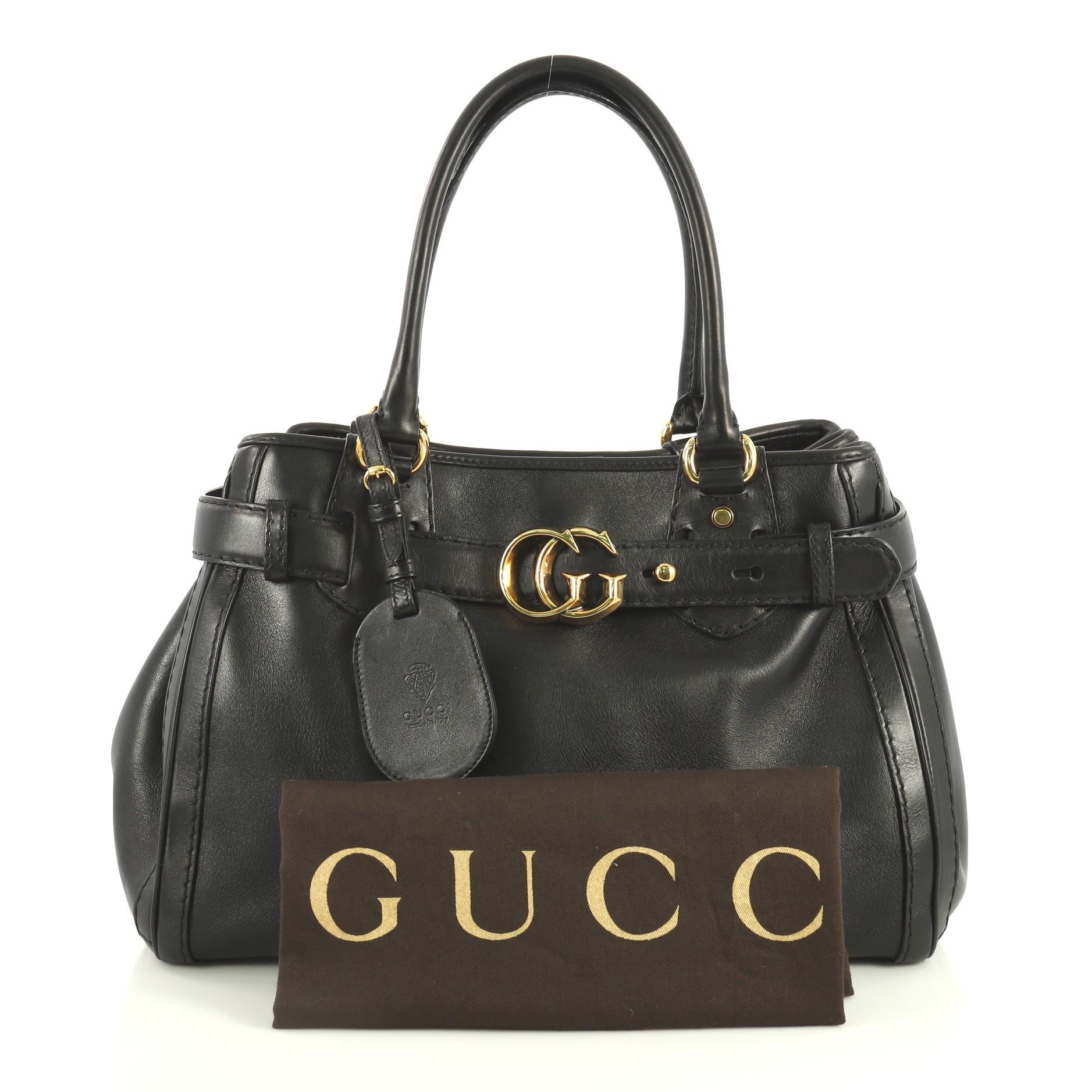 This Gucci GG Running Tote Leather Medium, crafted in black leather, features dual rolled leather handles, top belt with loops and interlocking GG buckle, protective base studs, and gold-tone hardware. Its magnetic snap button closure opens to a