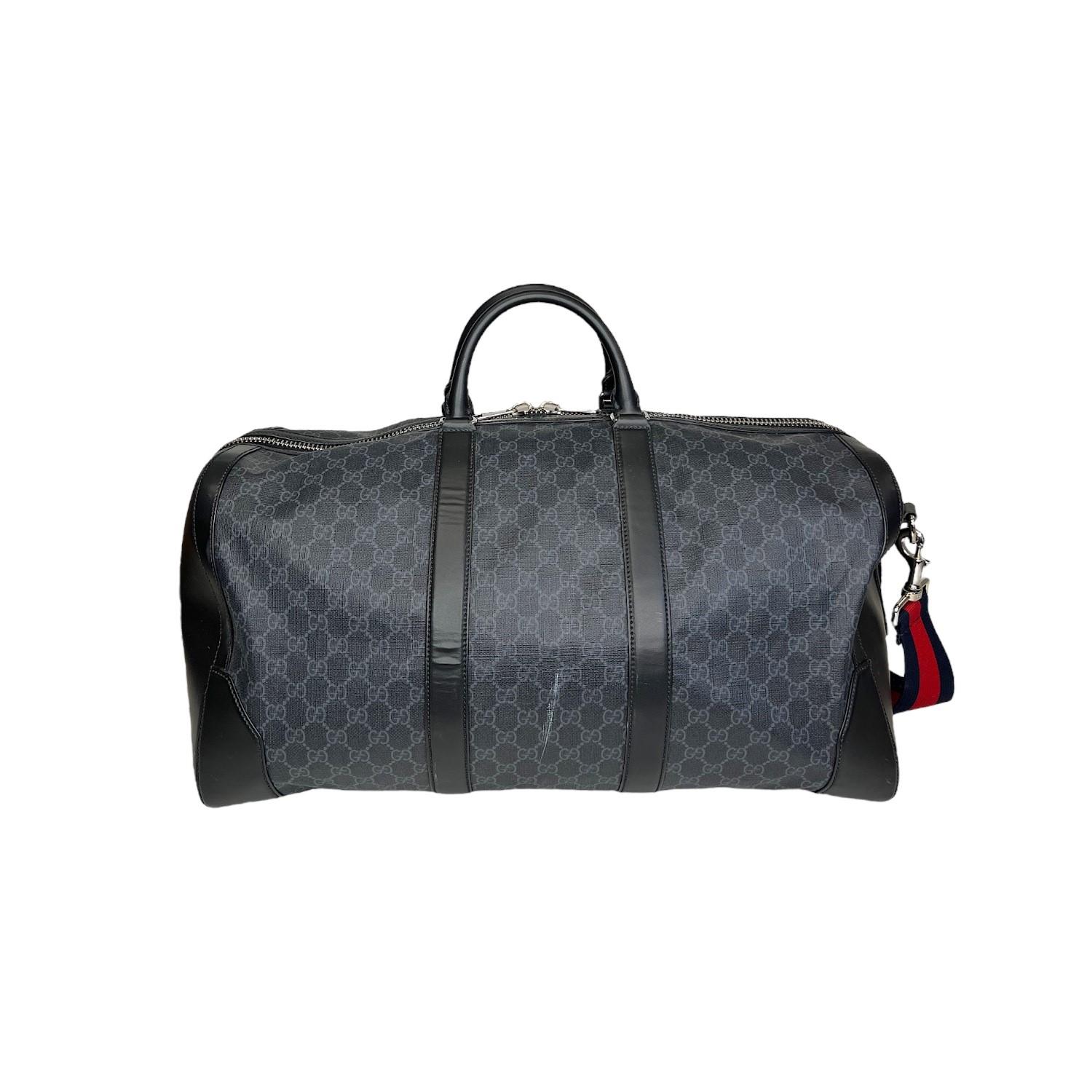 This Gucci GG Supreme Carry-On Duffle Bag was made in Italy and it is finely crafted of the Gucci GG Supreme canvas exterior with black leather trimming and silver-tone hardware features. It comes with a removeable and adjustable red and blue
