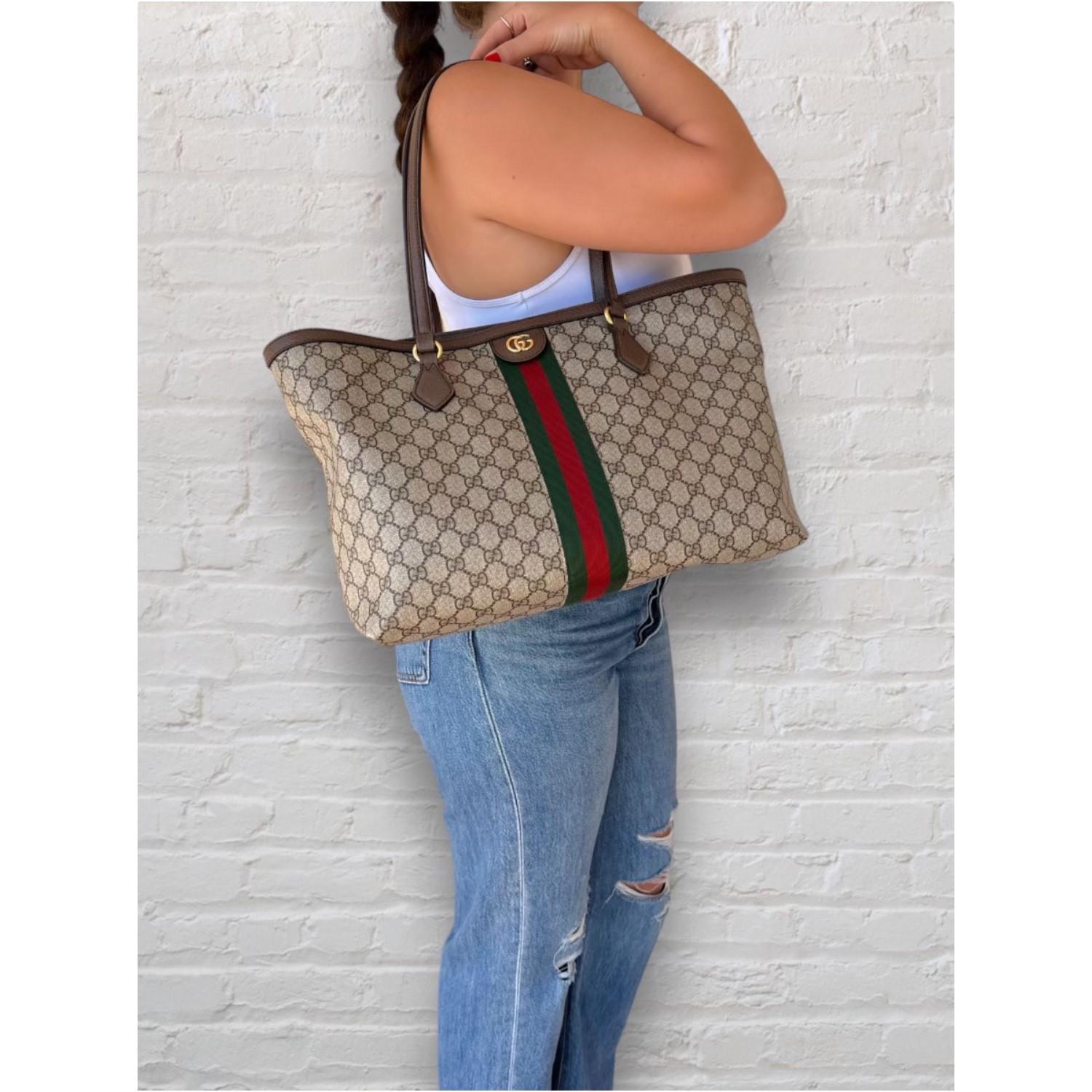 This Gucci GG Supreme Medium Ophidia Tote was made in Italy and it is finely crafted of the classic Gucci GG Supreme coated canvas exterior with leather trimming and gold-tone hardware features. It has a magnetic top closure that opens up to a very