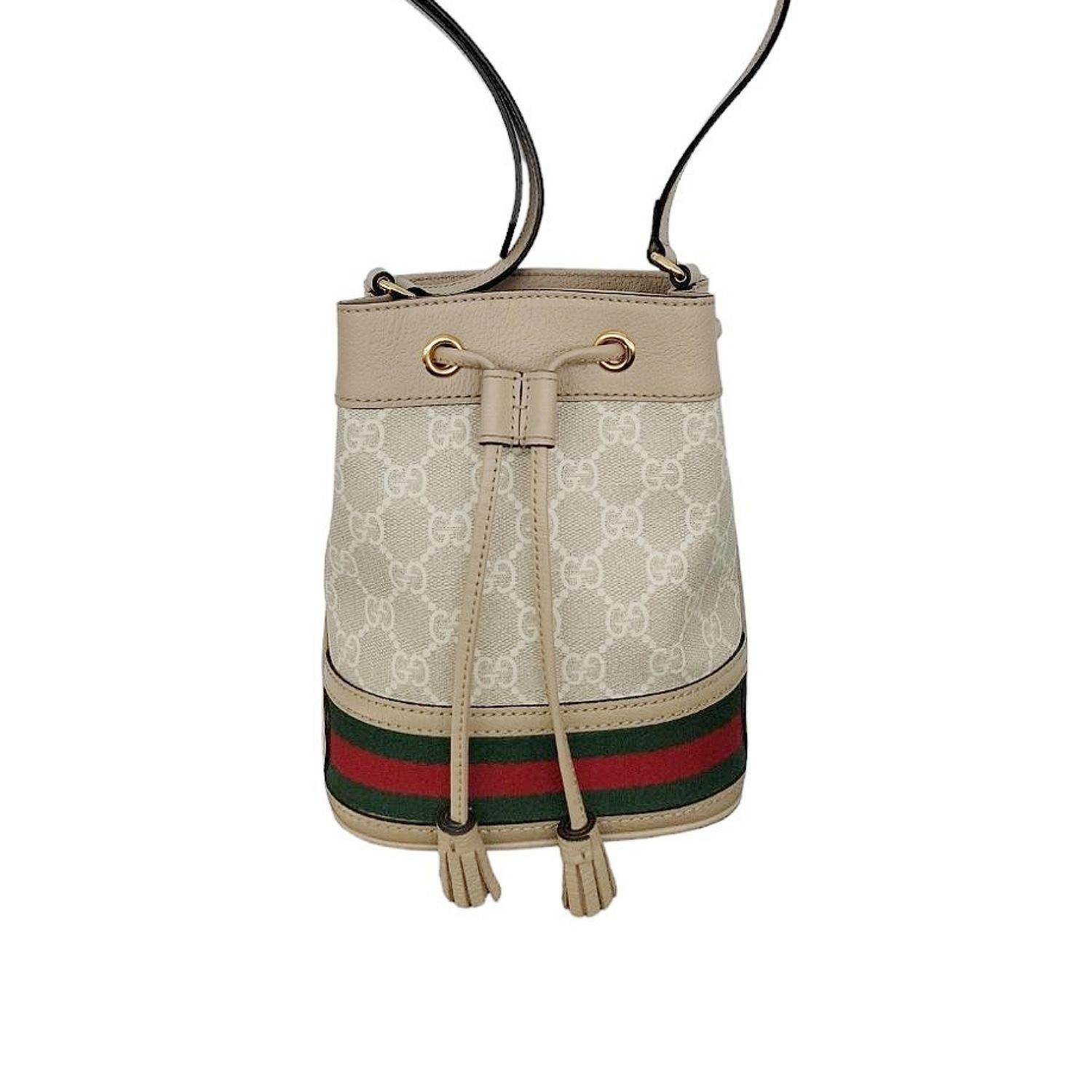 Gucci GG Supreme Mini Ophidia Bucket bag. It is crafted from beige and white GG Supreme canvas and oatmeal leather trim with a green and red web stripe accent. It has gold-tone hardware, a drawstring closure, a cotton linen lining, and an adjustable