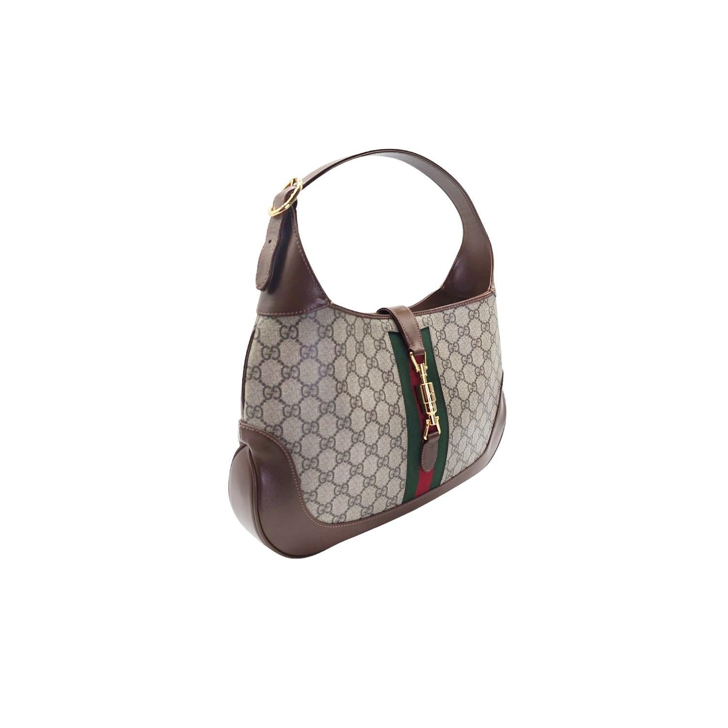 Schwelgen Sie in Luxus mit dieser Gucci GG Supreme Monogram Azalea Jackie 1961 Medium Hobo. Das kultige GG Monogram aus beschichtetem Canvas in Braun auf Beige wird durch einen auffälligen roten und grünen Webstreifen und einen sattbraunen