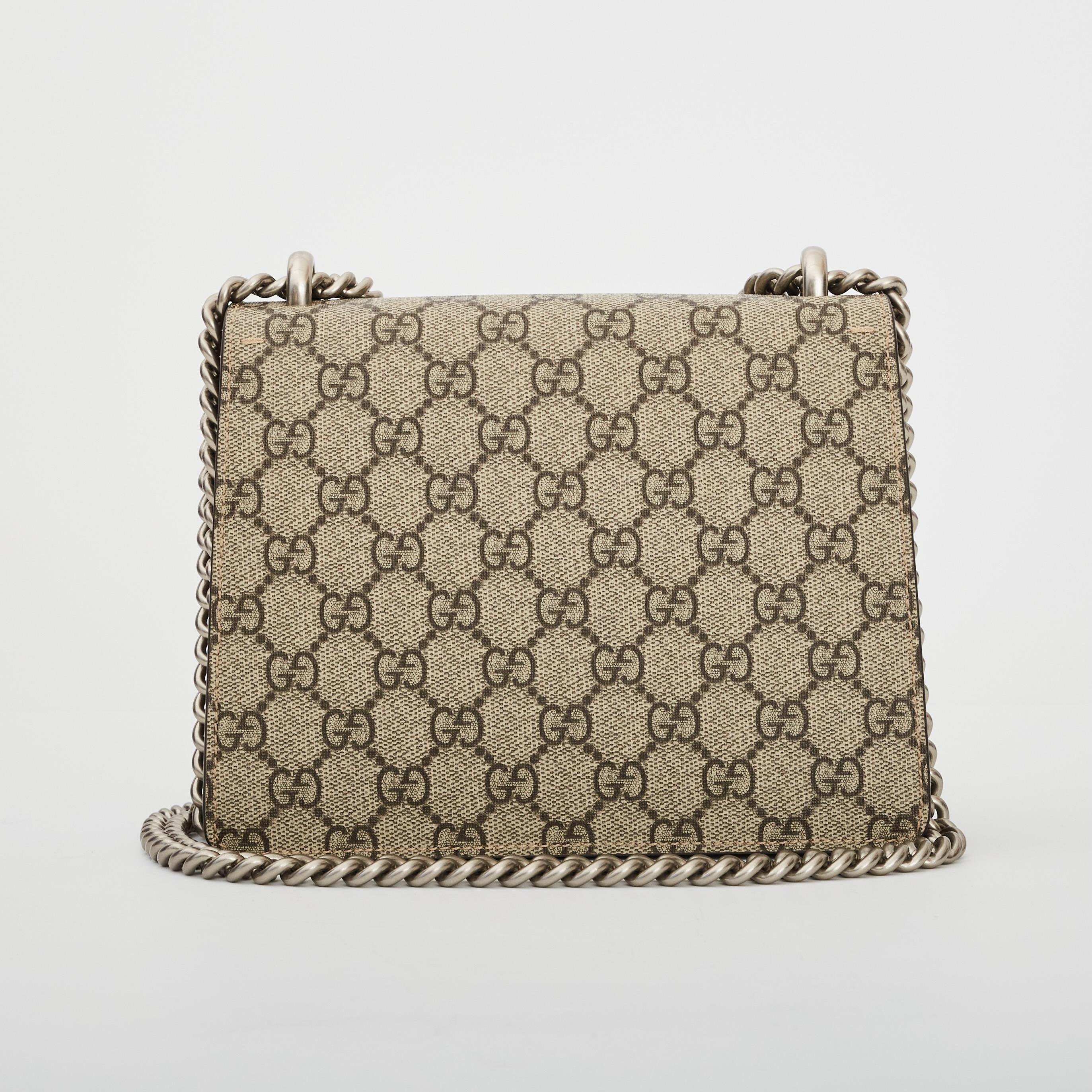 This bag is made of traditional Gucci GG monogram supreme canvas. This shoulder bag features an aged silver chain shoulder strap, and a textured horseshoe tiger spur closure. The double flap opens to reveal an exterior taupe brown suede flap and a