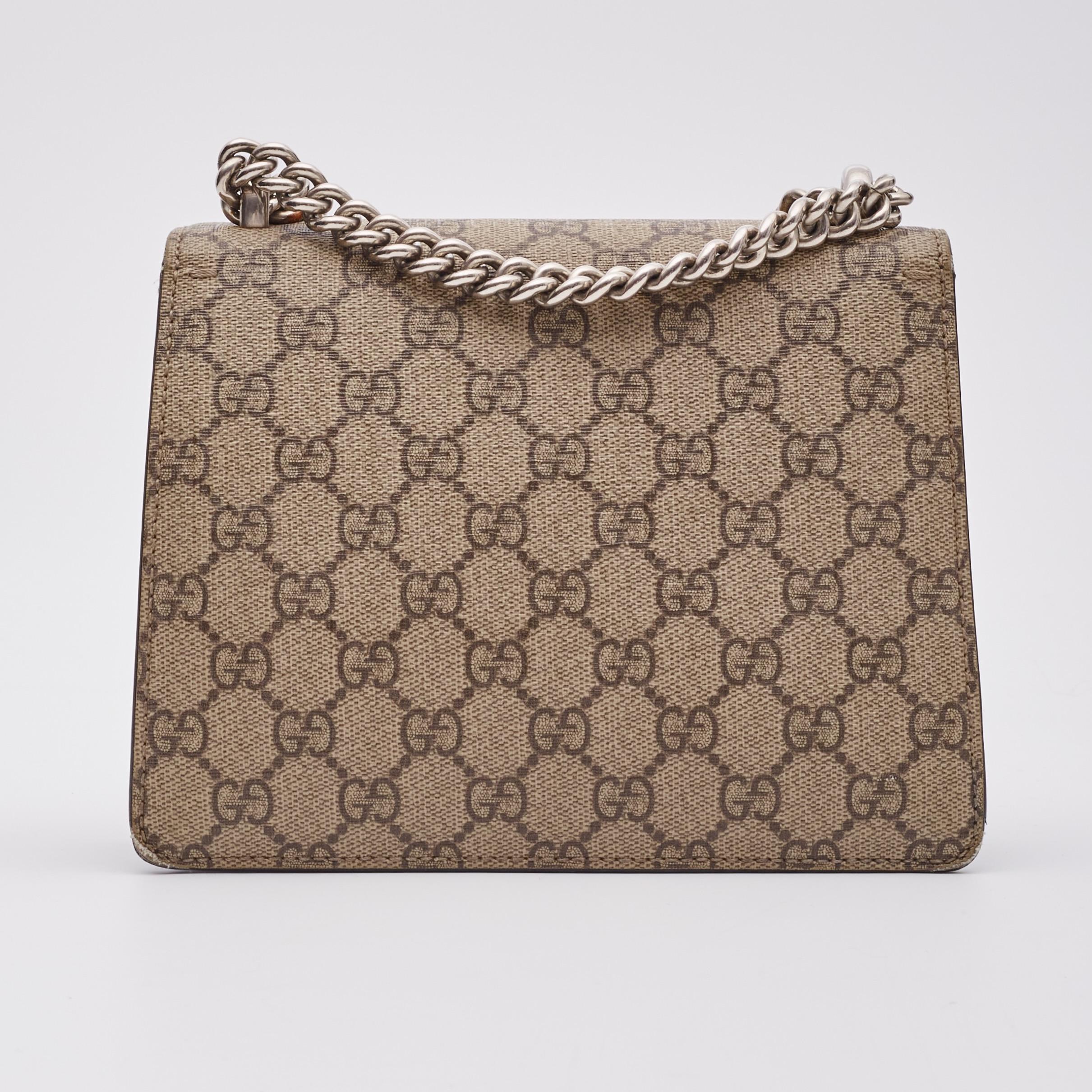 This bag is made of traditional Gucci GG monogram supreme canvas. The bag features an aged silver chain shoulder strap, and a textured horseshoe tiger spur closure. The double flap opens to reveal an exterior black suede flap and a coated canvas