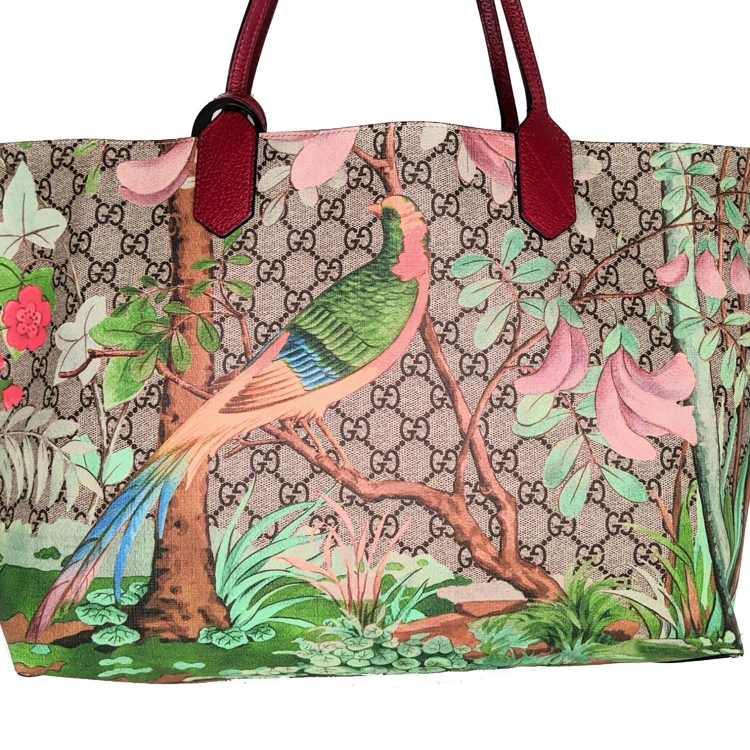 This chic tote is crafted of signature GG Supreme canvas printed with contemporary birds and greenery. The tote features red calfskin leather shoulder straps and a broad open top that reveals a spacious beige suede interior with zipper and patch