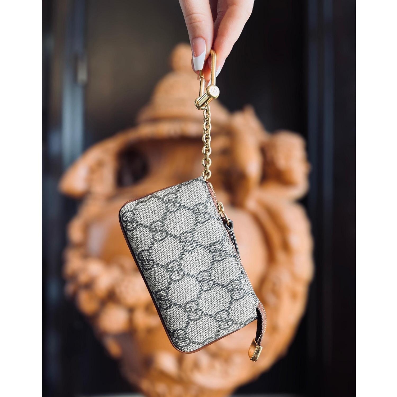 GUCCI GG Supreme Monogram Key Case in Brown. This stylish key case is crafted of Gucci GG monogram-coated canvas with an all-around dark brown leather trim. The case unzips with an overextended zipper to a brown fabric interior featuring a gold