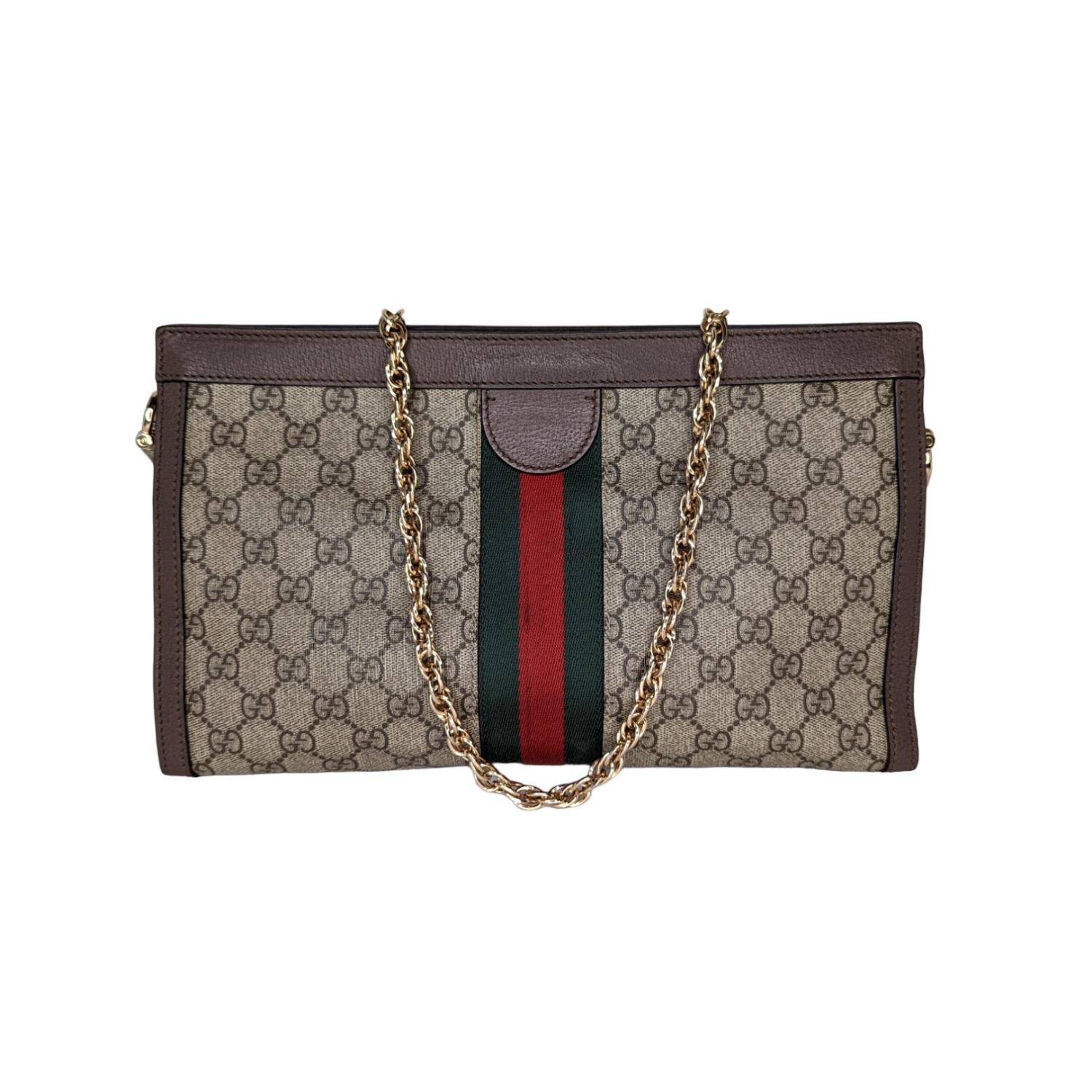 This chic shoulder bag is finely crafted of brown on beige and ebony Gucci GG supreme monogram coated canvas with a web stripe detail. The bag features a polished gold chain strap, GG logo, and hardware. The magnetic top opens to a partitioned blue