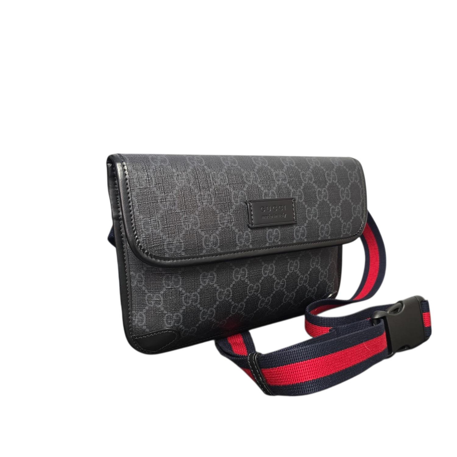 La borsa Gucci GG Monogram Web Slim Belt è sapientemente realizzata in tela spalmata GG Supreme Monogram nera e grigia con finiture in pelle. È dotata di una tracolla regolabile in tela a righe rosse e blu e di una minuteria argentata. La patta