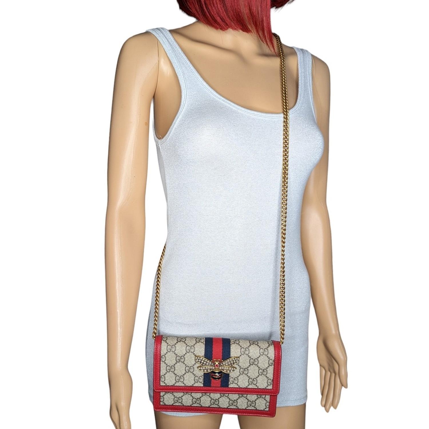 This shoulder bag is crafted of monogram coated canvas. The shoulder bag features a red leather trim, an aged-gold crossbody chain and a front flap with an enameled aged gold metallic bee encrusted with small pearls and faceted stones. The bag opens