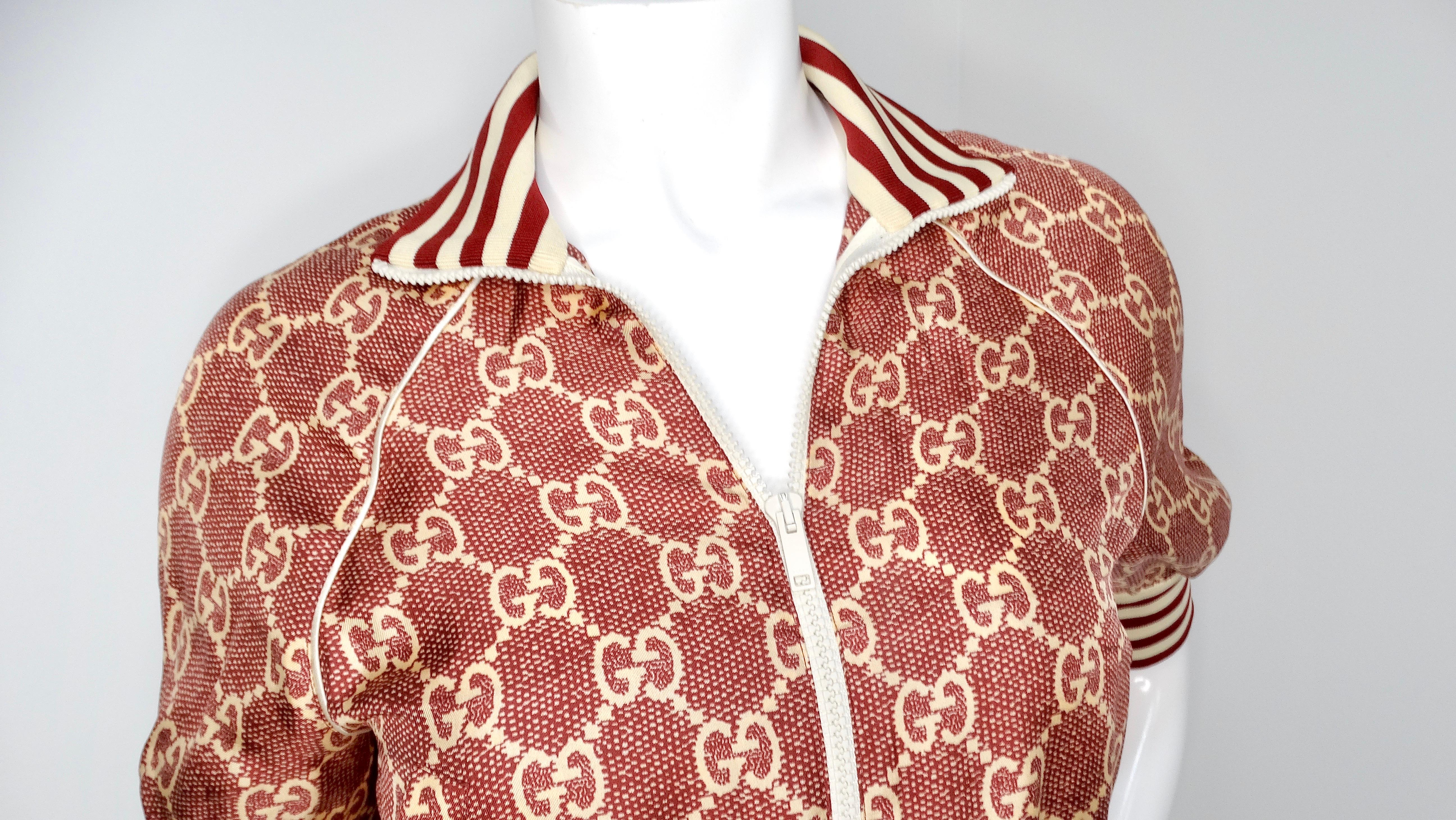 La veste de survêtement en soie bourgogne GG Supreme de Gucci, circa 2022, est une pièce luxueuse et élégante qui allie parfaitement l'athleisure à la haute couture. Confectionnée en 100 % soie et fabriquée en Italie, cette veste arbore le motif GG