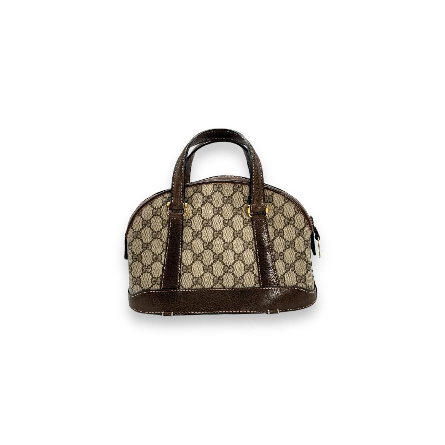 Upgrade your style with the Gucci GG Vintage Brown Monogram Dome Top Handle Bag. Crafted in Italy with GG Web Coated Canvas and Leather Trim, this designer bag features a zip closure at the top, a suede interior lining, and gold-tone hardware. Stay