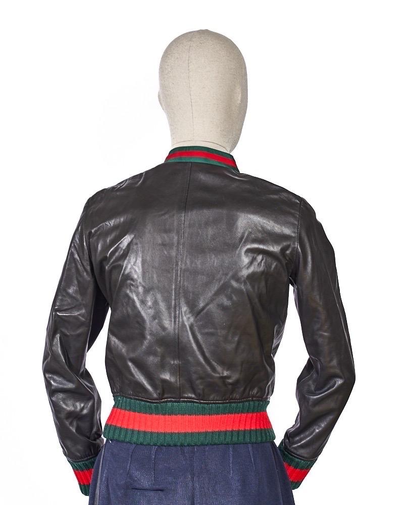 Giacca firmata Gucci, realizzata in pelle nera con inserti in tessuto web e arricchito da rouches sul davanti. Presenta dos bolsos cómodos y un cierre de cremallera. Internamente foderato di rosa, Taglia 38\XS. El artículo se presenta en perfecto