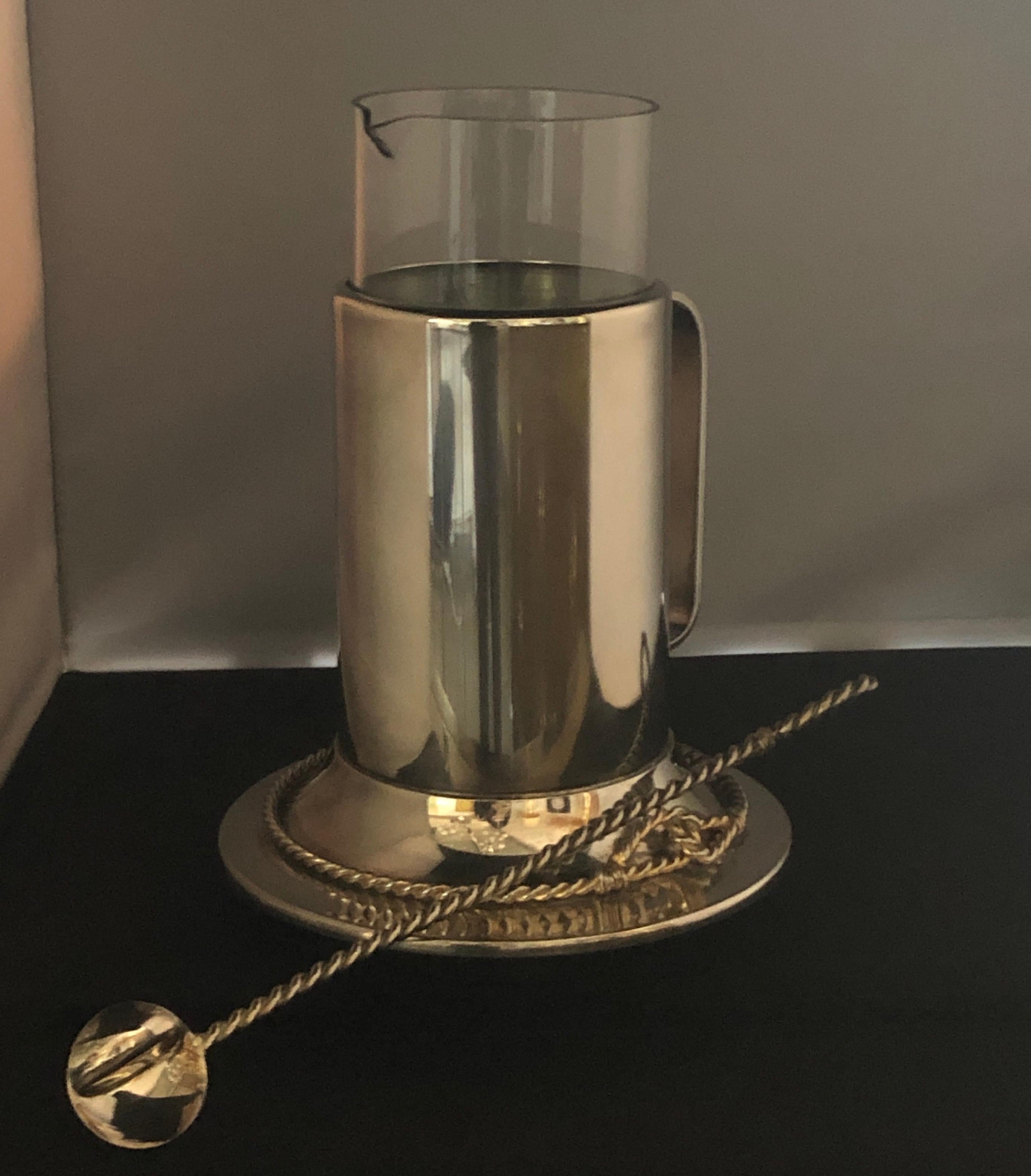 Offered is a Mid-Century Modern or late 20th century nautical themed glass encased in silver and gold plate vintage signed Gucci martini pitcher with matching French twist also in gold and silver long spoon. The glass pitcher can be removed and
