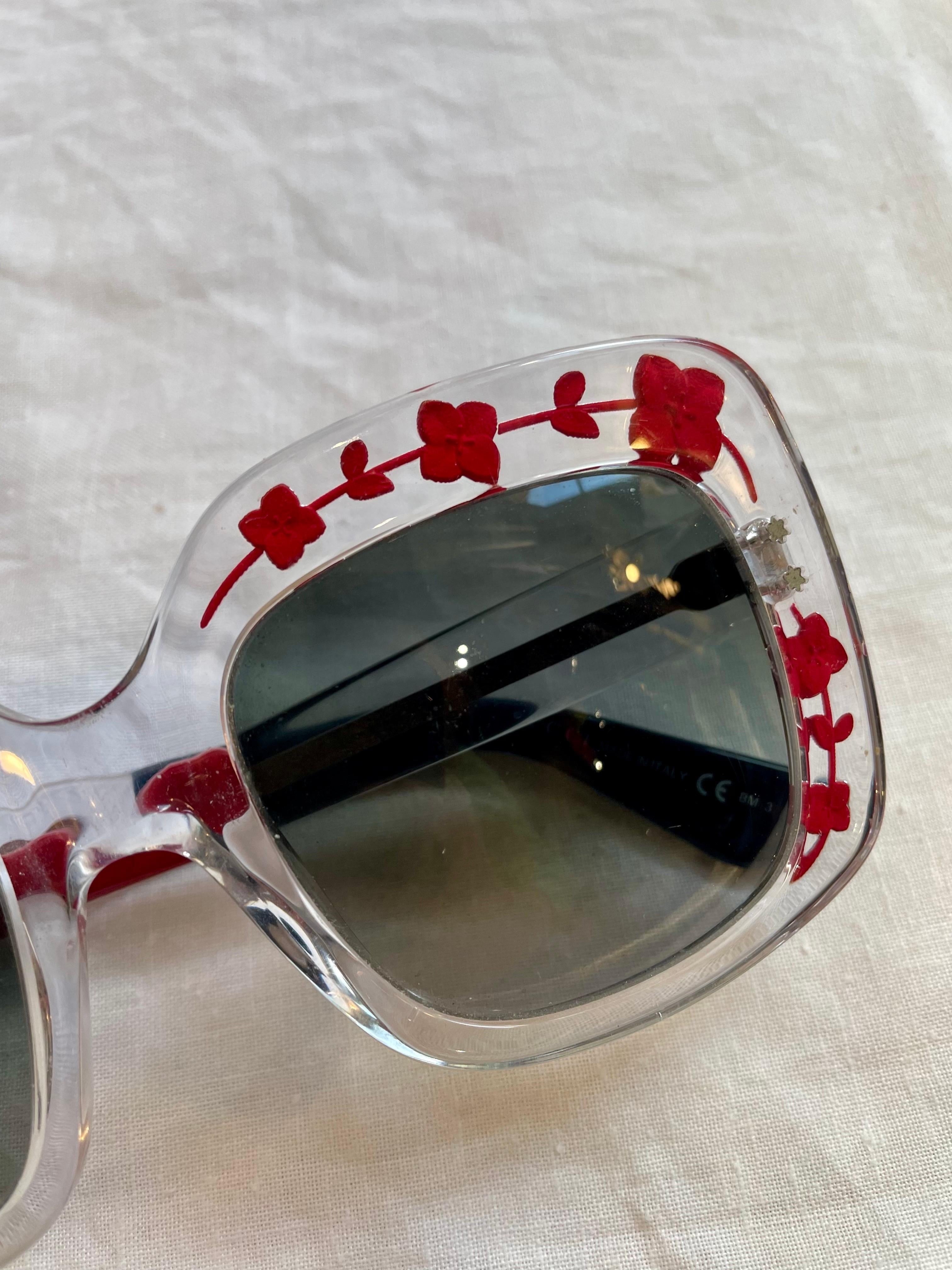 Gucci glasses in transparent plastic with red flowers engraved inside. Gradient lenses on black. They show some signs of use on the lenses and temples as can be seen from the photos. 
With original case. 
16cm wide
7cm tall 
Rods 15 cm