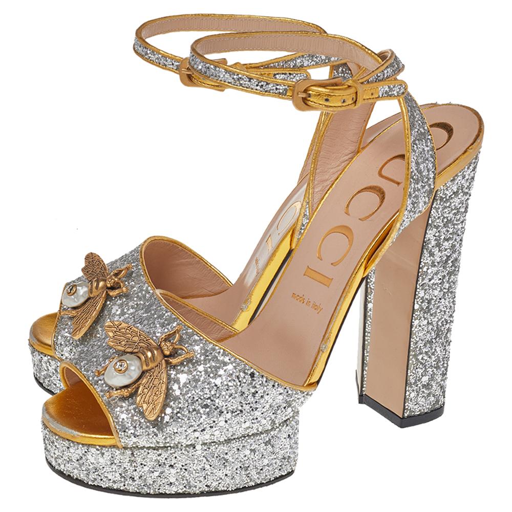 Glam up your style with confidence as you wear these gorgeous sandals from Gucci. Flamboyantly made using silver-gold glitter fabric and leather with the Soko Bee motif adorned on the wide upper strap, these sandals are the talk of the town. You