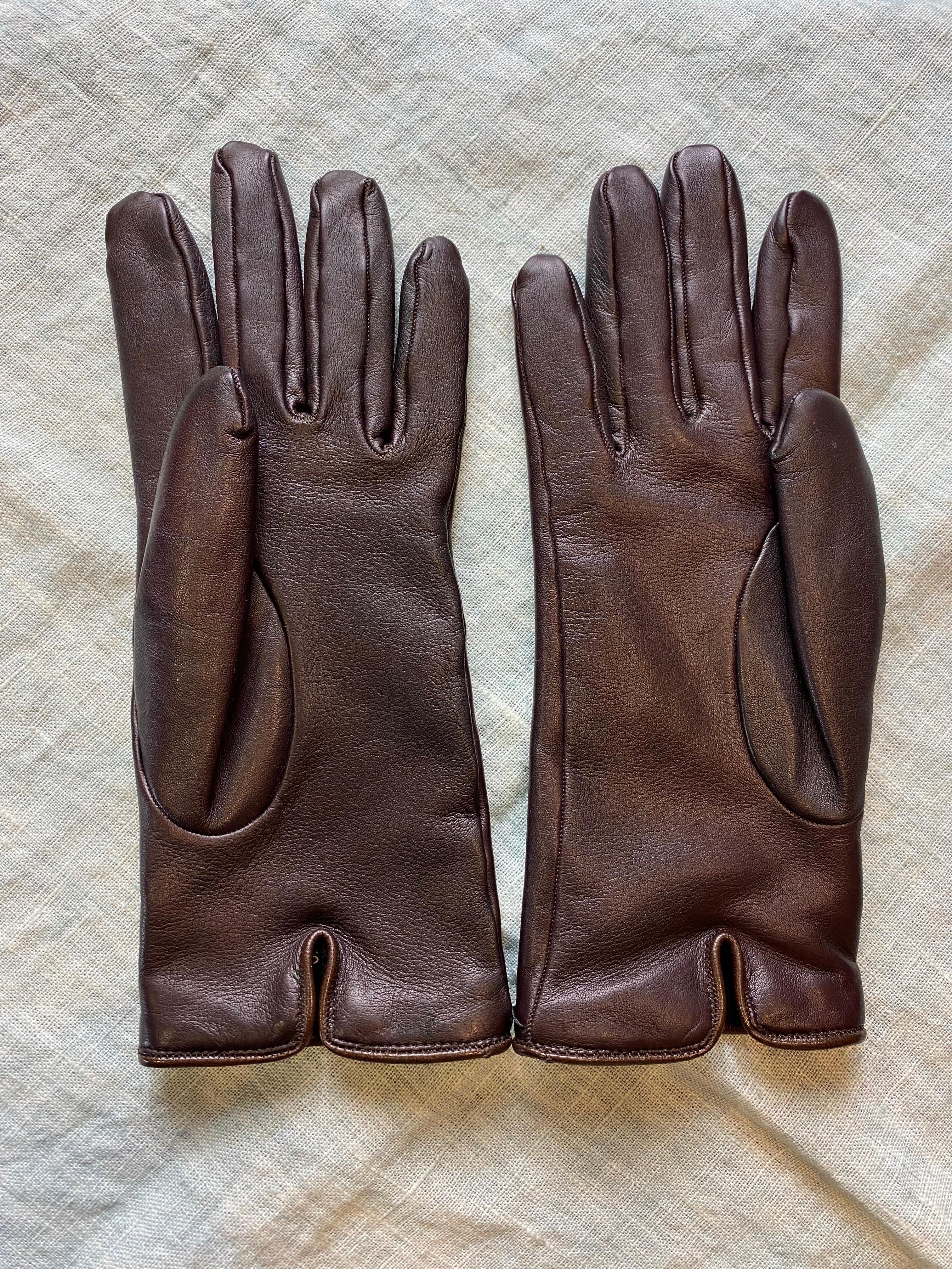 Guanti Gucci in pelle marrone con una leggera sfumatura bordeaux. Piccolo dettaglio in metallo argentato e interno in cashmere.
È in buone condizioni, presenta piccoli segni di normale utilizzo.
Lunghezza 25 cm
Polso cm 9
Taglia 7.5 (M)