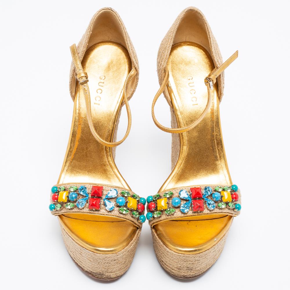 Ces chaussures compensées signées Gucci sont parfaites pour les soirées d'été. Ils sont fabriqués en jute et en cuir doré et présentent des orteils ouverts, des empeignes embellies, une bride de cheville et des talons compensés.

