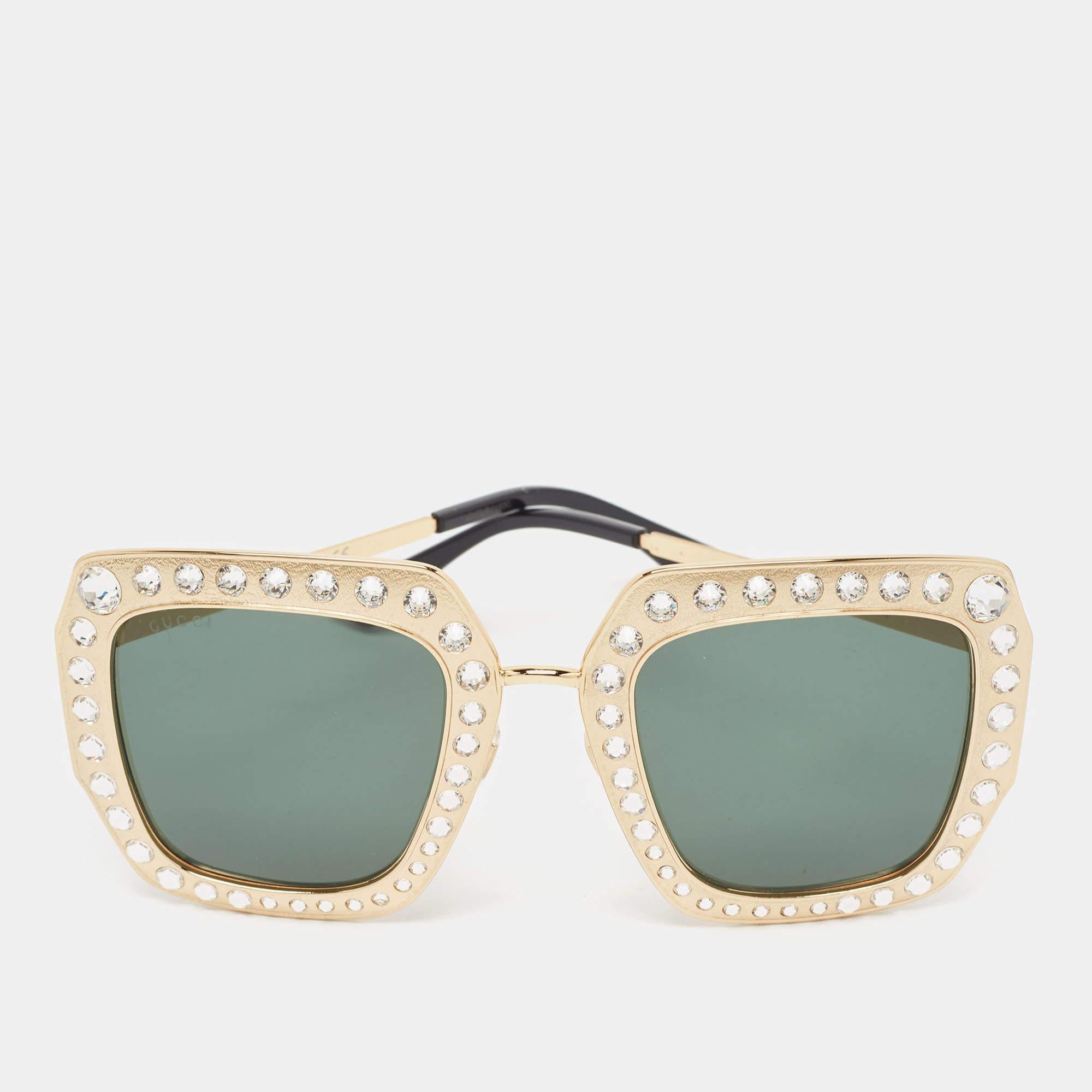 Cette paire de lunettes de soleil Gucci est idéale pour une journée au soleil ou des séances photos en intérieur. Il s'agit d'un accessoire à part entière. La monture en or est ornée de cristaux sur le devant.

Comprend : Étui d'origine, chiffon à