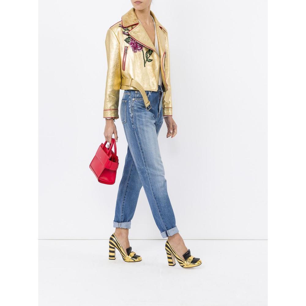 Gold leather short biker jacket from Gucci.
Asymmetrical zip front closure
Two front zip pockets
Red piping
Belt loops with matching removable belt at waist
Zip cuffs
Sequin front and back embellishements
Oversized fit
Red fabric lined
Made in