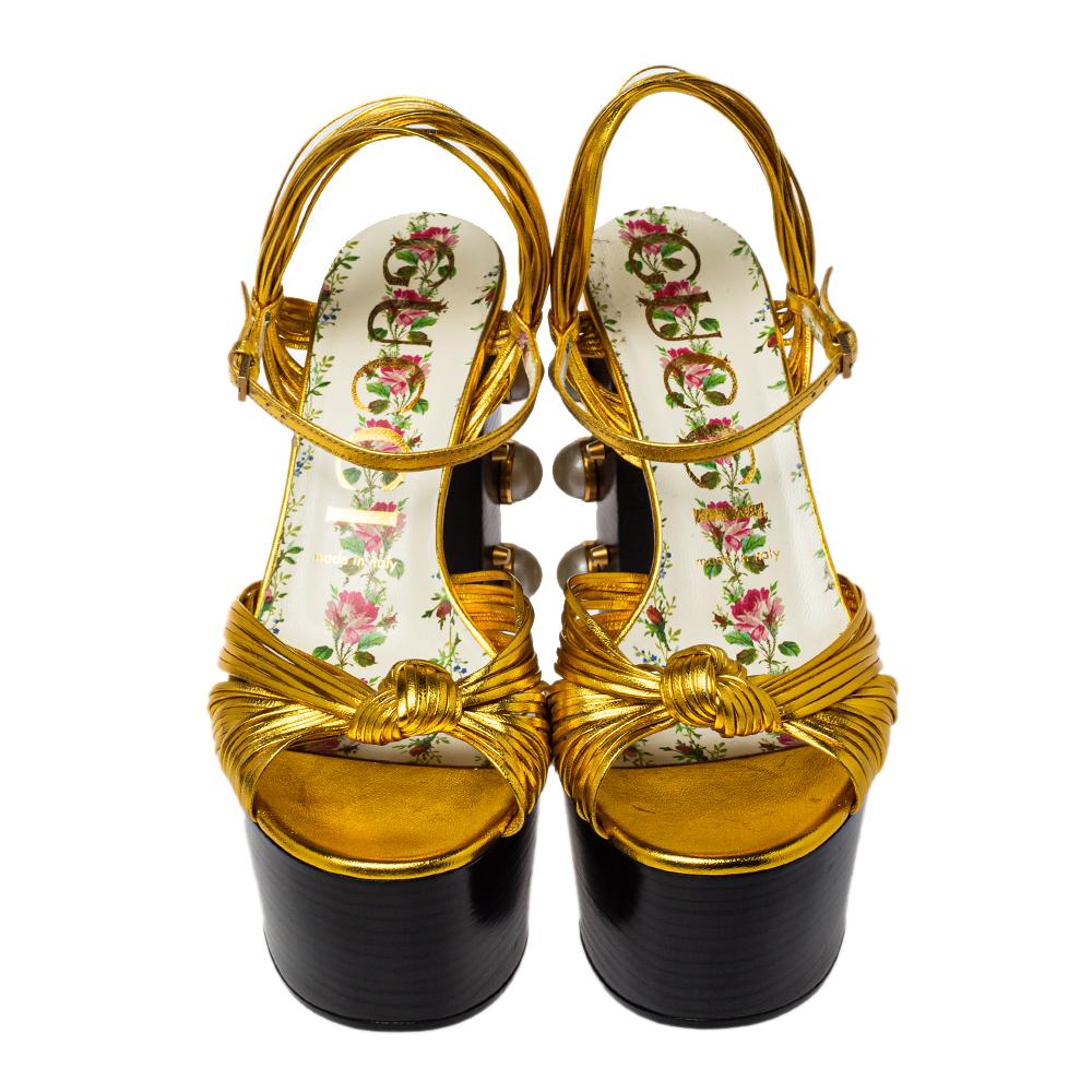 Be on-trend and fashion-forward with these gorgeous platform sandals from Gucci! The shoes feature gold knotted leather straps with pearl studs on the tall heel. The insoles are made from floral leather. The bold silhouette, color, and detail of
