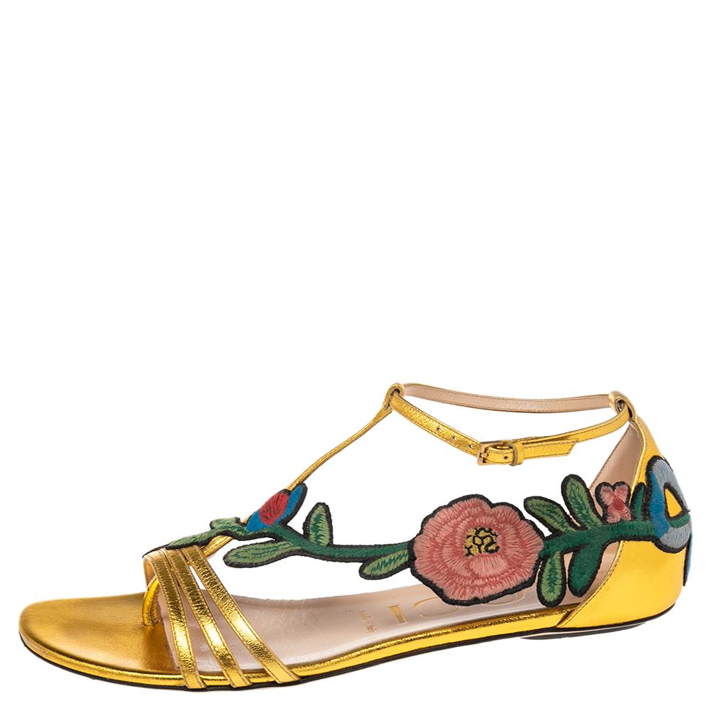 Wear luxury with a touch of high fashion by choosing these flats from Gucci. They are crafted from leather in an open-toe T-strap silhouette and detailed with floral embroidered patches that extend from the vamps to the counters. They are complete