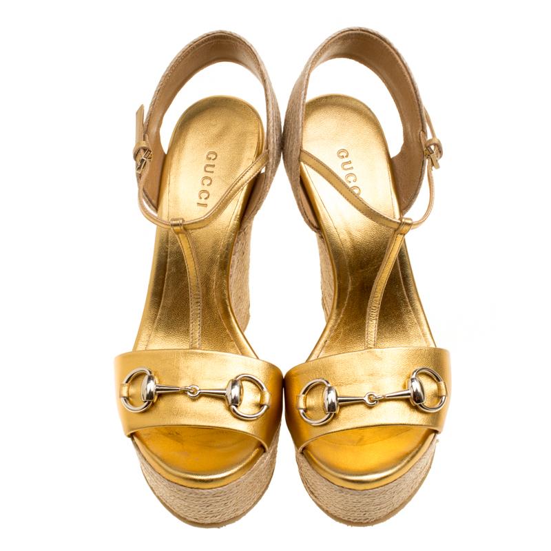 Gucci's timeless wedge sandals are finished with the label's iconic gold horse-bit detail in gold-tone on the front strap. They're crafted from metallic gold leather and feature architectural raffia wedges that are balanced by generous platforms for