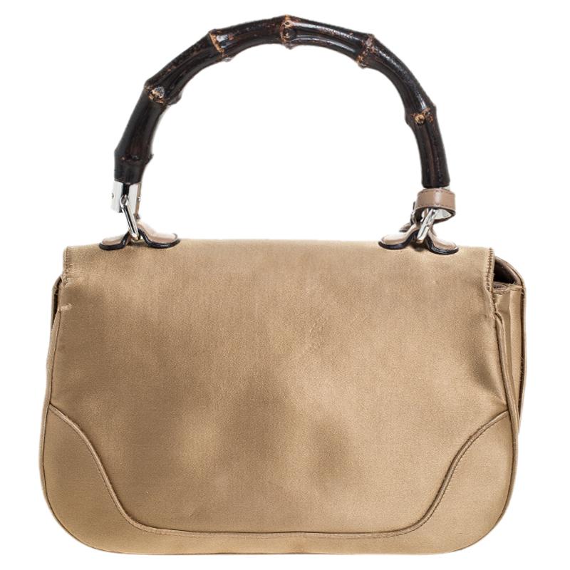 Chic and stylish, this Gucci bag looks distinct with its bamboo-inspired design. Crafted from satin and leather, it is provided with silver-tone hardware. It features a bamboo top handle, a detachable shoulder strap, tassels, and a flap closure with