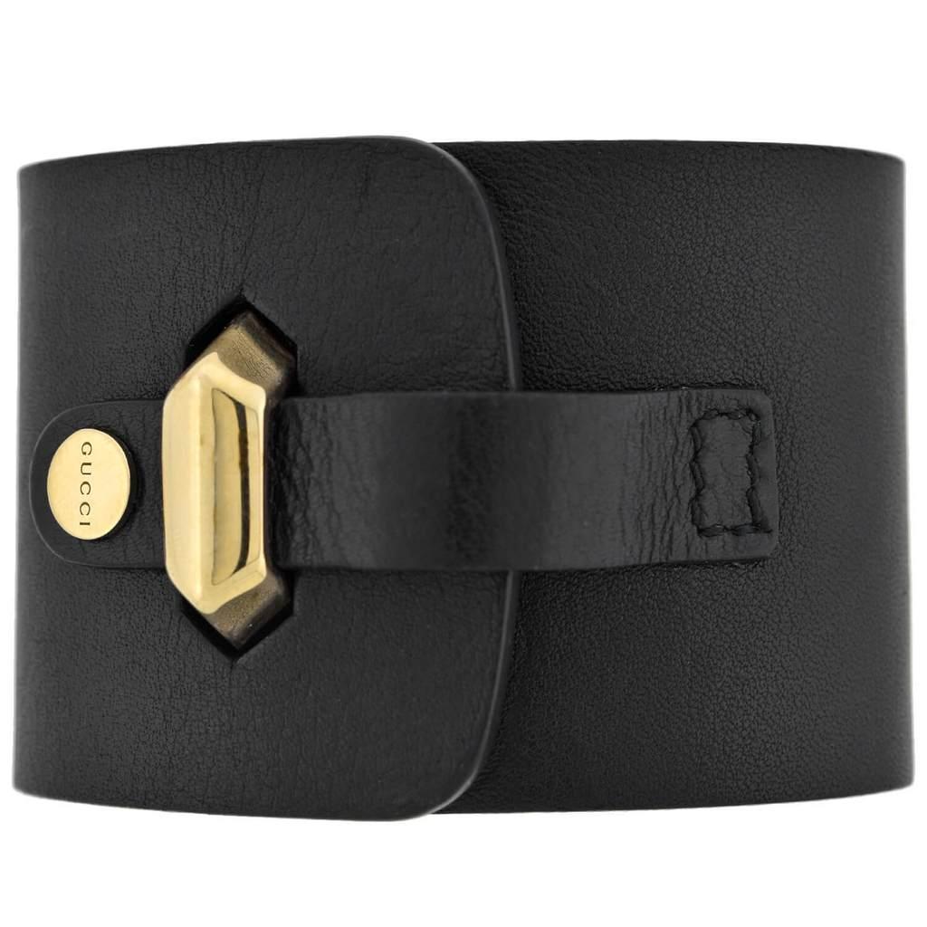 An absolutely fabulous bracelet from legendary fashion house Gucci! This stylish piece is comprised of chunky gold-tone pyramidal links at the center of a wide, black leather band. The three bold links have an elongated shape with a subtly faceted