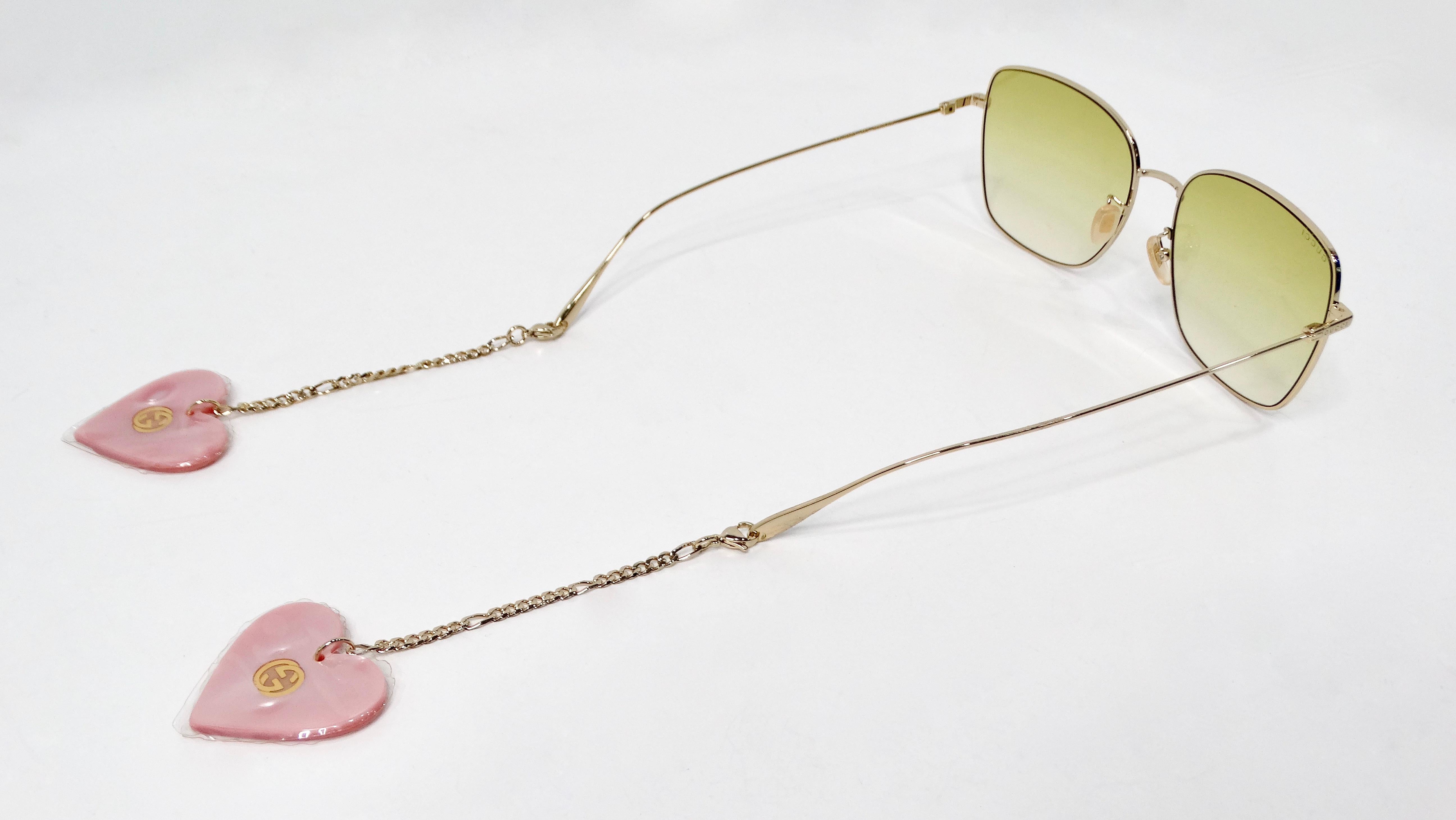 Ti presentiamo gli occhiali da sole quadrati color oro di Gucci, un accessorio straordinario che combina il lusso con un tocco giocoso. Caratterizzati da un'elegante montatura quadrata in metallo dorato e lenti colorate verdi, questi occhiali da