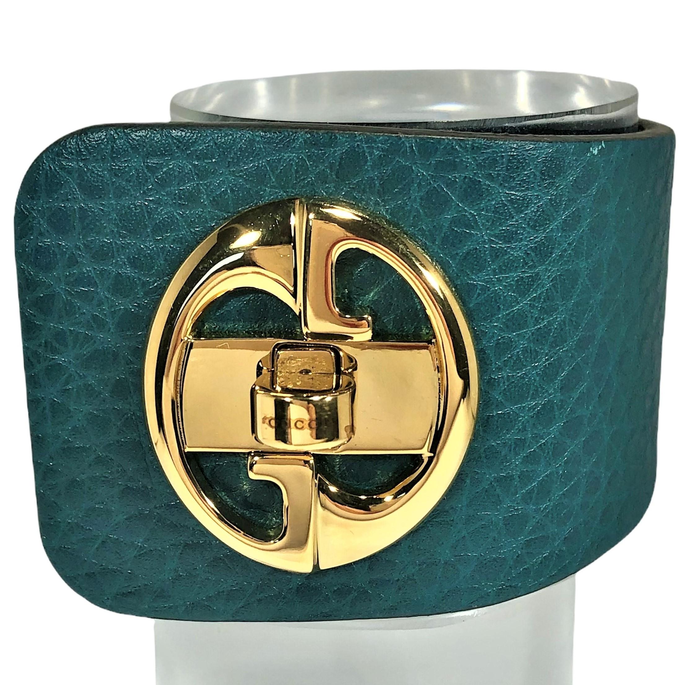 Made in Italy by Gucci, this gold tone turnkey style leather cuff bracelet has never been worn. The  bracelet flares from just under 2 inches 
(1 15/16 inches) at the widest point down to 1 1/2 inches at the back. The turnkey clasp makes this