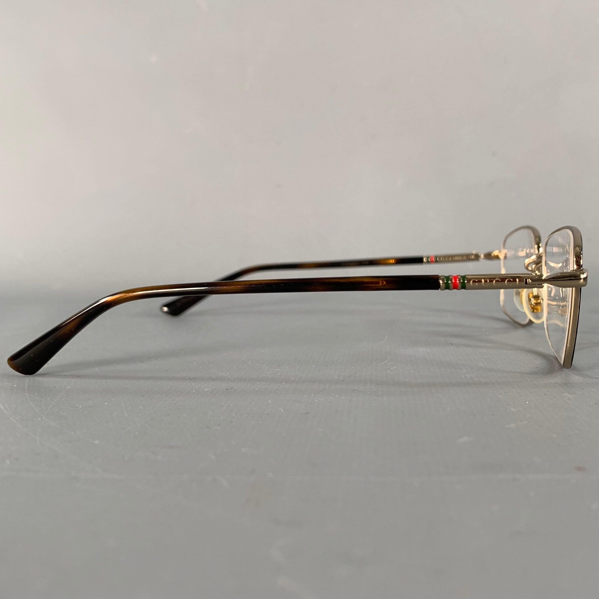 Montature Gucci
in metallo dorato con aste in acetato tartarugato a forma di rettangolo e dettagli a righe rosse e verdi. Nota: queste montature contengono lenti correttive, che dovranno essere cambiate da un ottico prima di essere indossate. Made