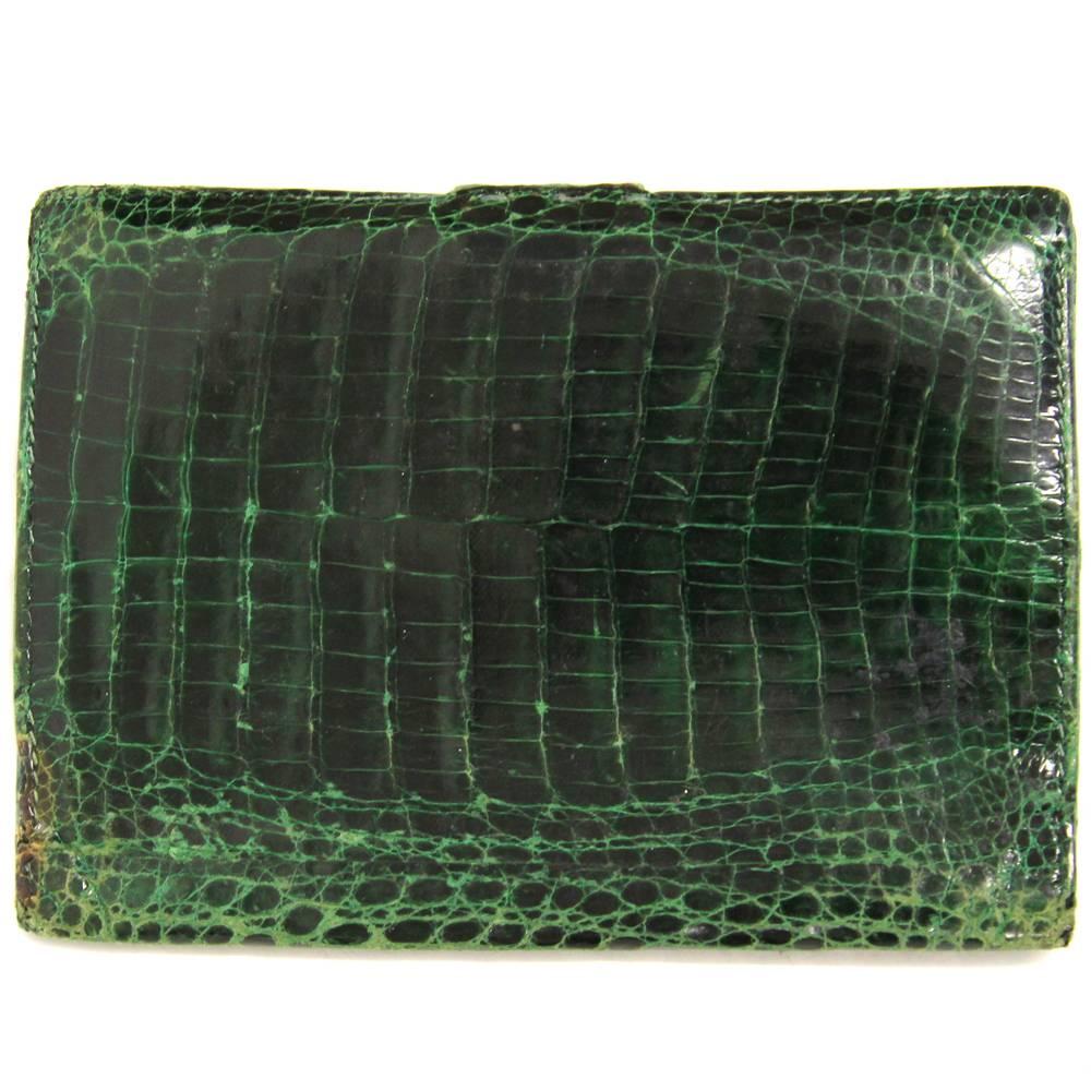 Marvelous Gucci cardholder made with crocodile leather in a deep green color, with golden metal logo on the front. Pression button closure. The item is vintage, it was produced in the 70s and shows signs of wear, especially on the edges and the