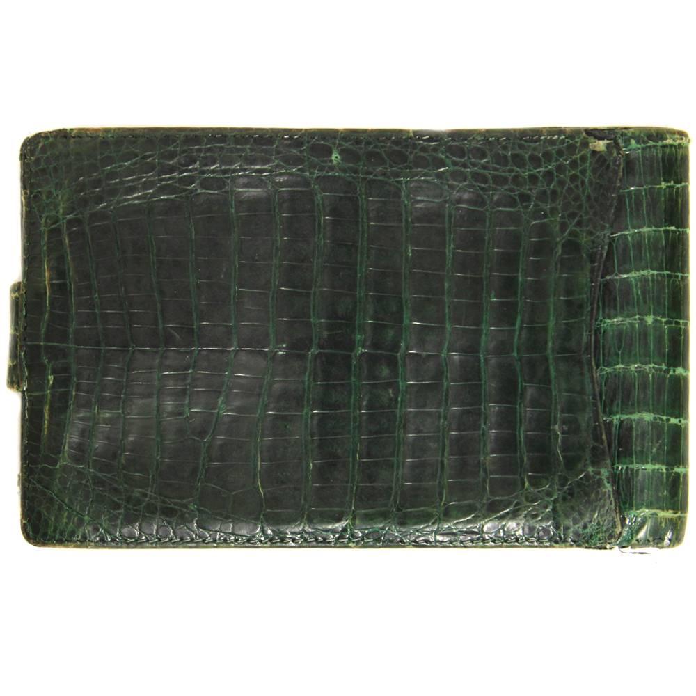 Marvelous Gucci check holder made with crocodile leather in a deep green color, with golden metal logo on the front. Pression button closure. The item is vintage it was produced in the 70s and shows evident signs of wear, especially on the edges and