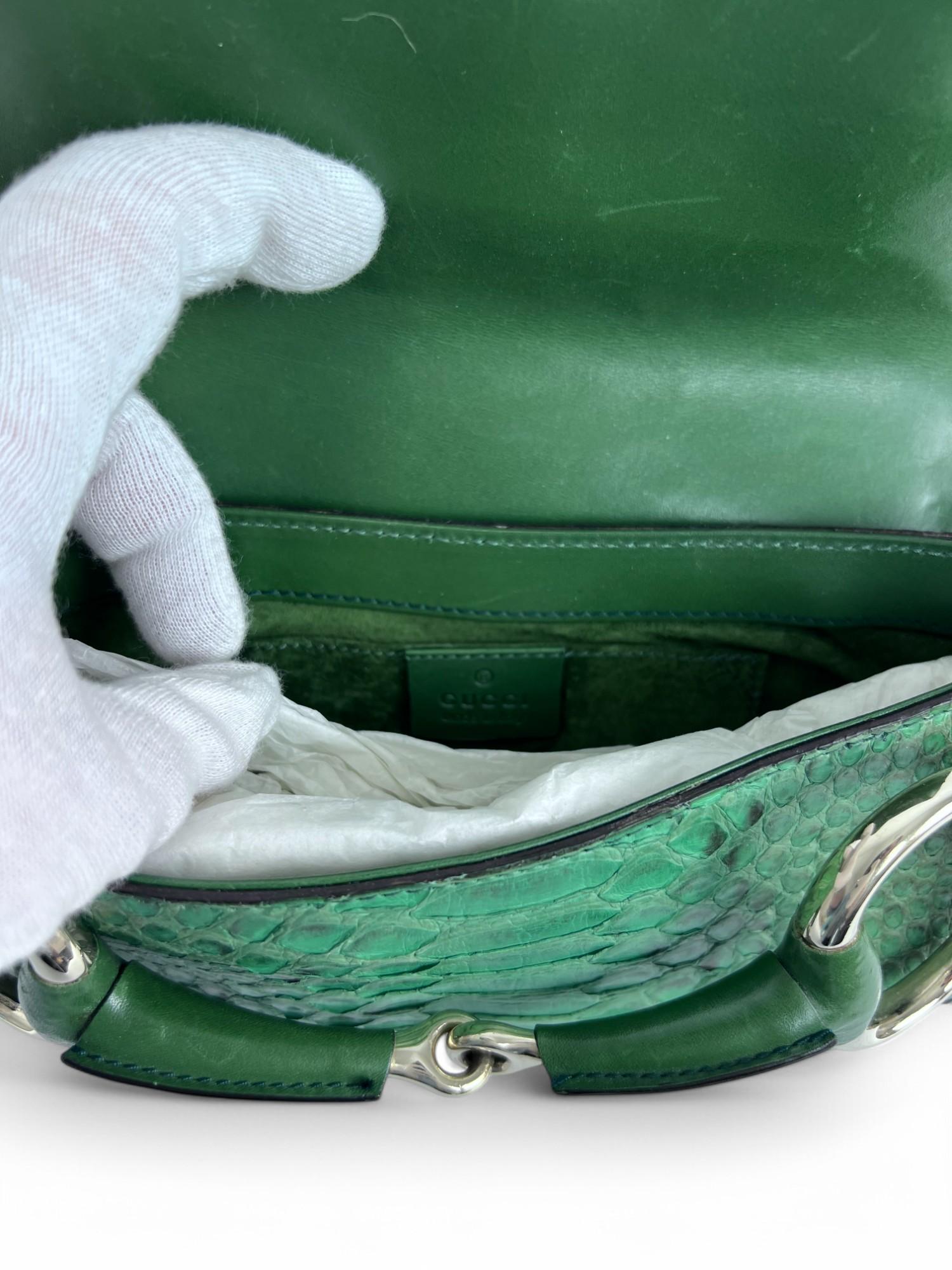 Exuding bold luxury and edgy sophistication, this Gucci Horsebit Chain Clutch is crafted from exotic green python leather, making it a striking statement piece. The signature oversized horsebit detail, rendered in sleek silver-tone metal, is
