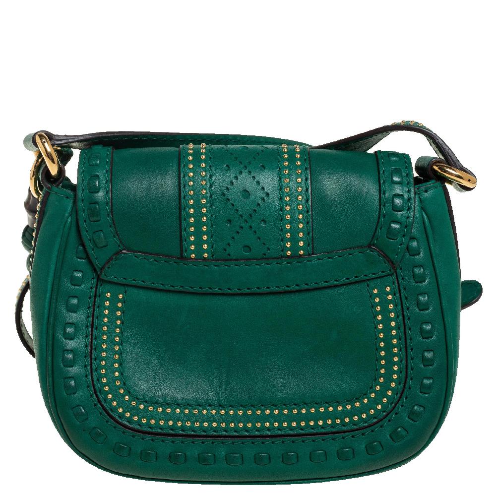 A gorgeous piece for style-conscious women, this small shoulder bag from Gucci is made with green leather. It is beautifully adorned with stud embellishments and two leather tassels detailed with bamboo and leather monkey fist. The flap features