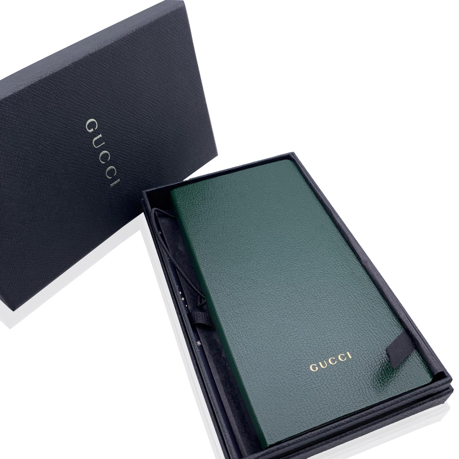 Gucci notebook with accordion card holder. Green cover. Gucci logo embossed on the front. Removable notebook with black pages on a side and accordion card holder on the other side. Elastic closure. Measurements: 7.25 x 3.5 inches - 18.5 x 8.9 cm.