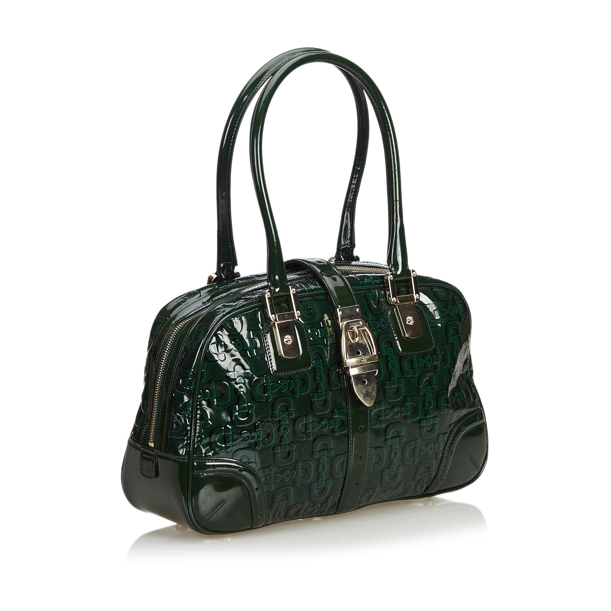 This shoulder bag features an embossed patent leather body with a horse bit pattern, rolled straps, a top strap with a belt buckle detail, a top zip closure, and an interior zip pocket. It carries as AB condition rating.

Inclusions: 
This item does