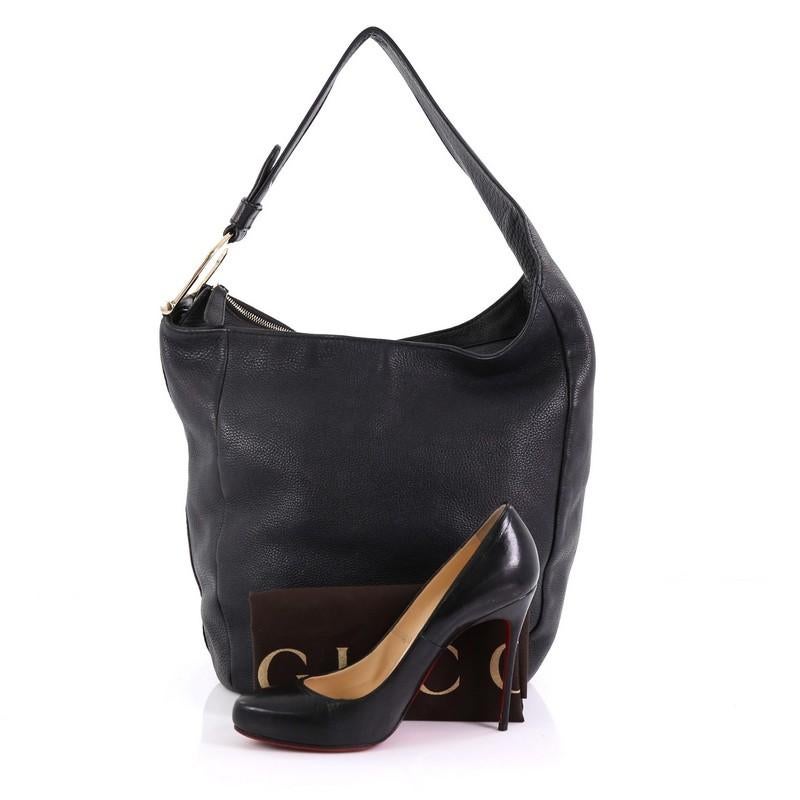 This Gucci Greenwich Hobo Leather Large, crafted in black leather, features a single asymmetrical looped leather handle with gold-tone spur detailing at the end and gold-tone hardware. Its top zip closure opens to a beige fabric interior with side
